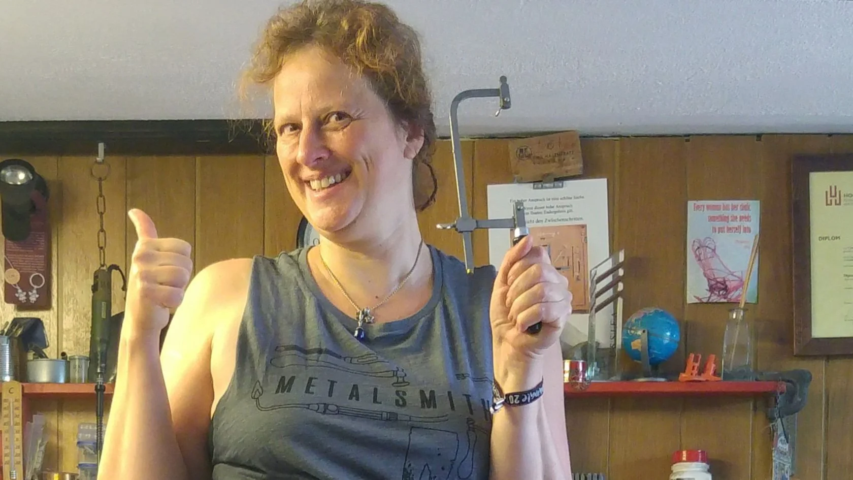 Diplom Designerein Cynthia Kurth im Goldschmiede Atelier mit einer Goldschmiedesäge zeigt Daumen hoch.