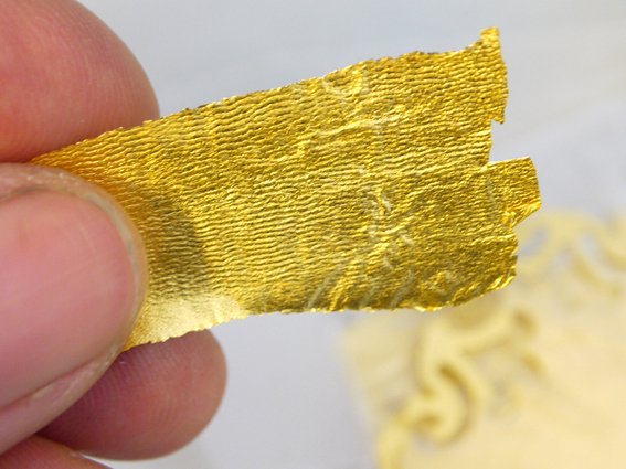 zwischen Daume und Zeigefinger halte ich einen zarten sattgoldenen Feingoldstreifen