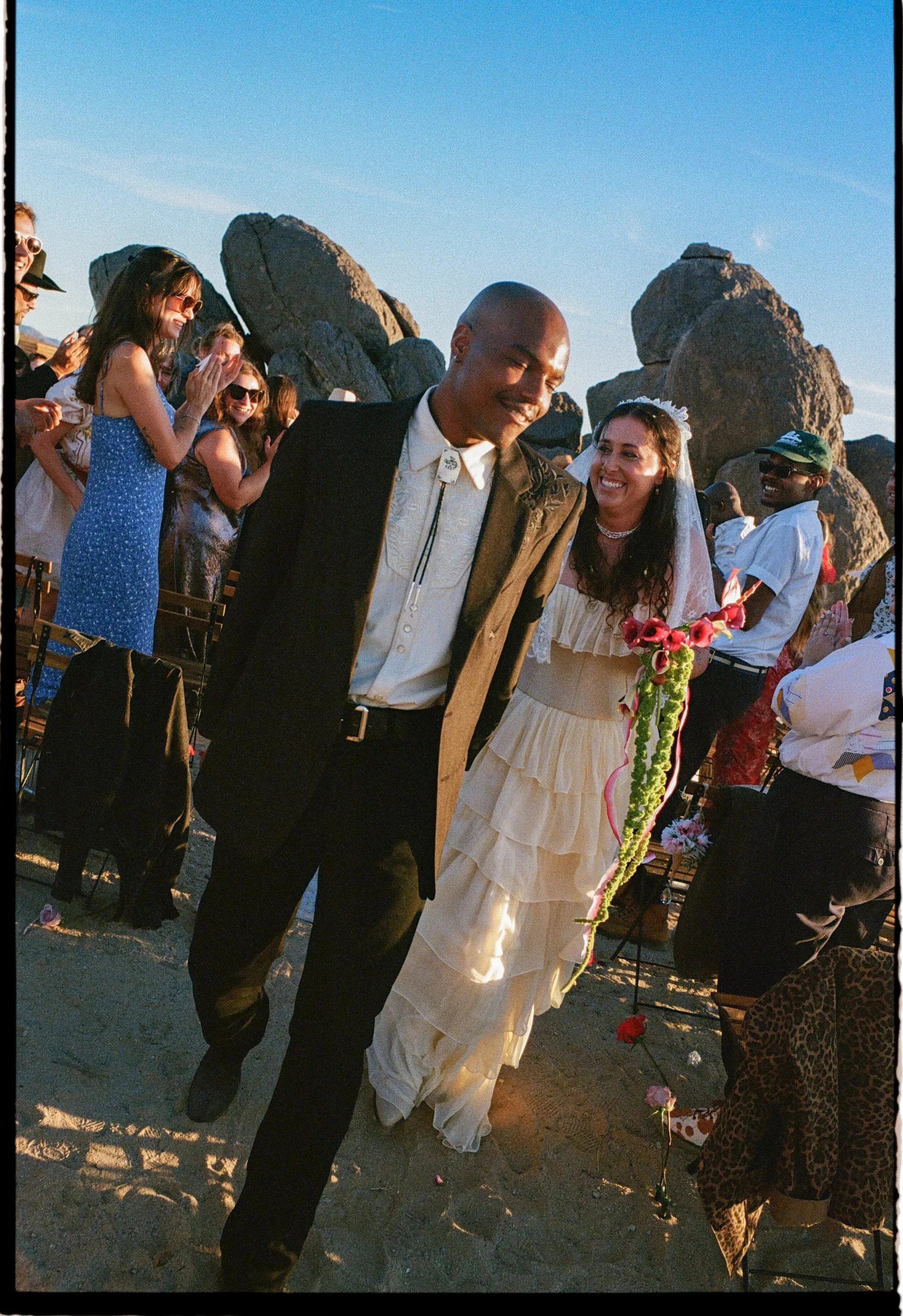 A bride and groom walk back down the aisle after getting married in the desert