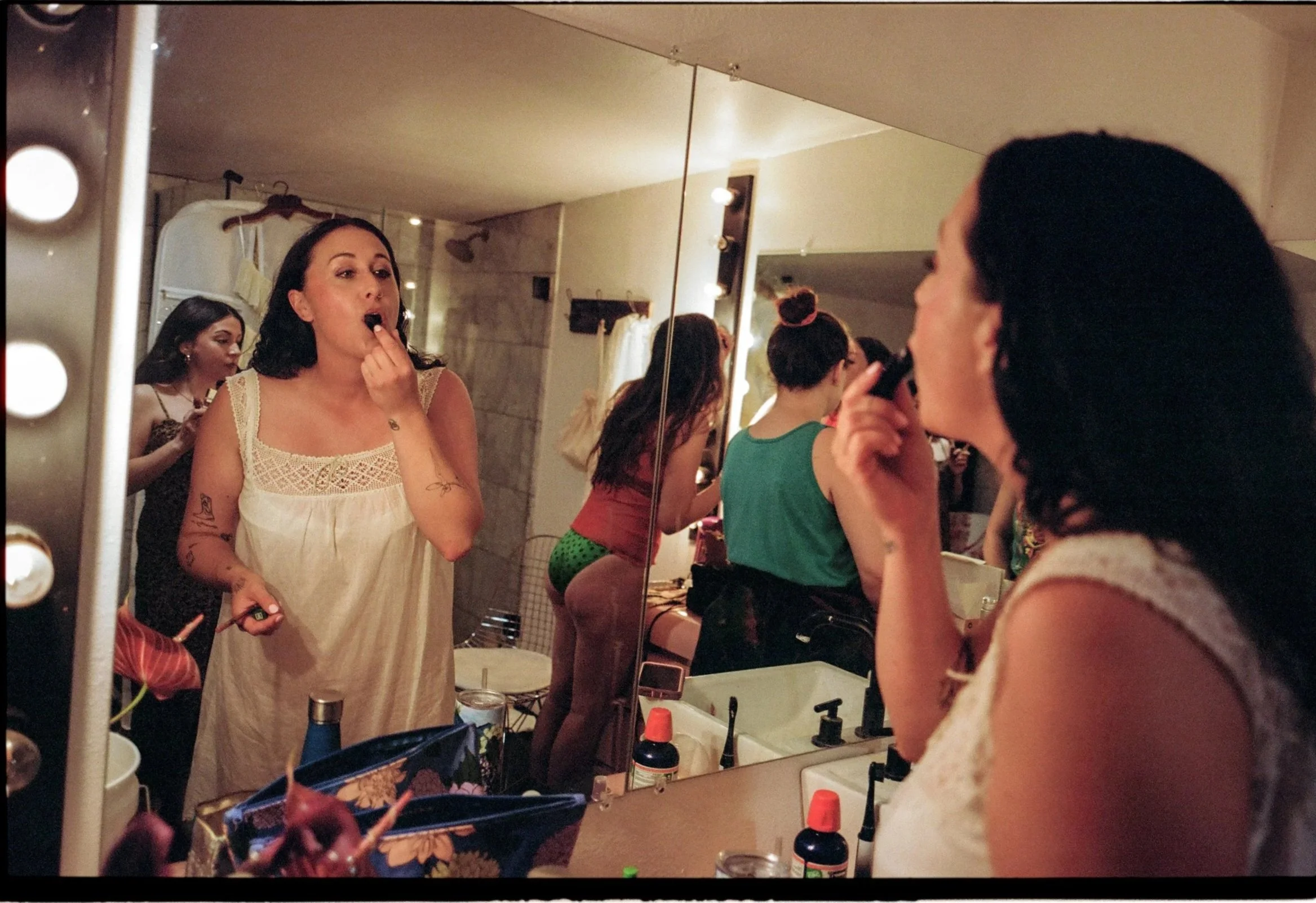 A bride putting on lipstick in a vintage nightgown while getting ready