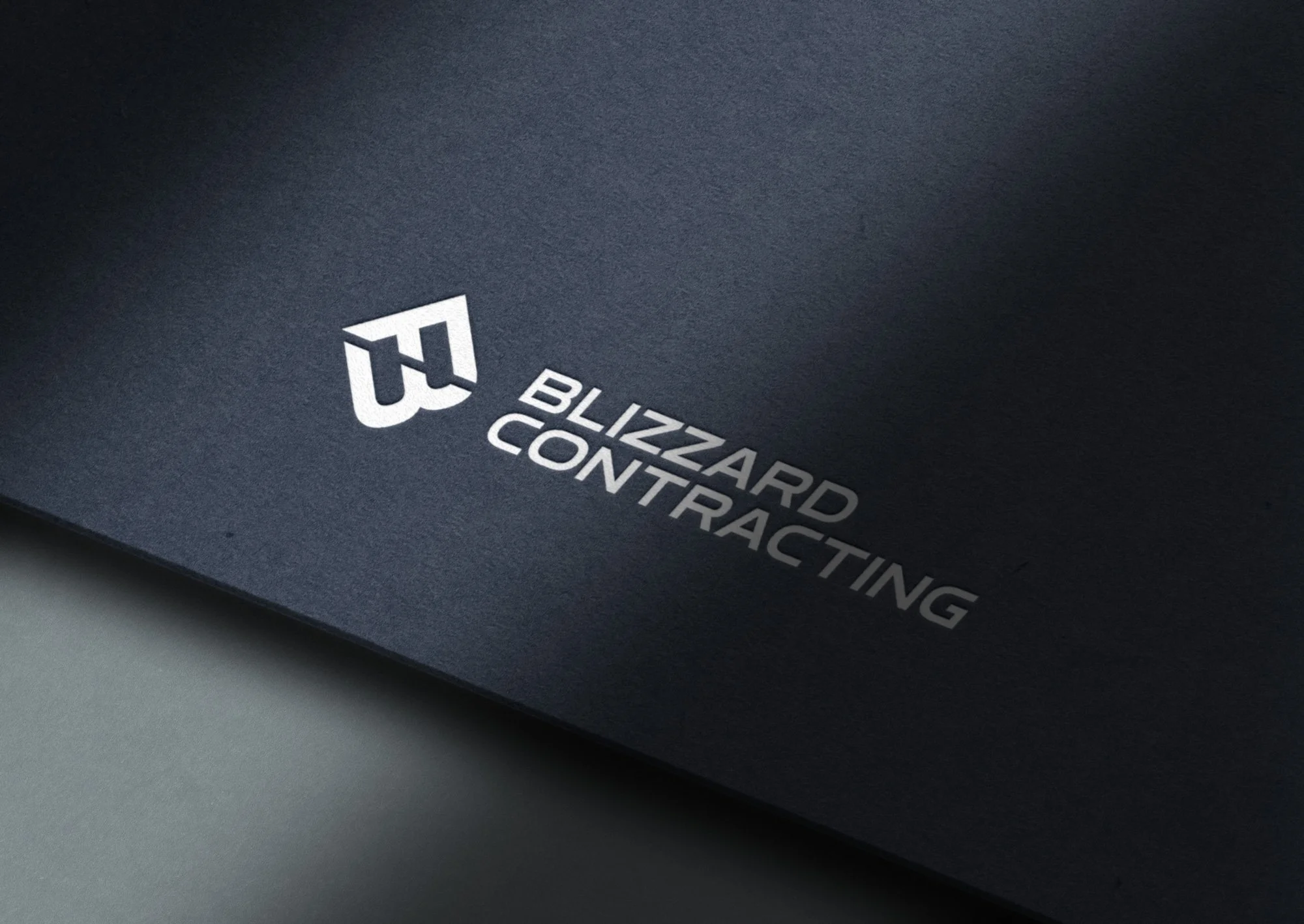 Close-up of a black card with white text that reads 'Blizzard Contracting' and a white icon logo in the shape of a stylized 'B'.