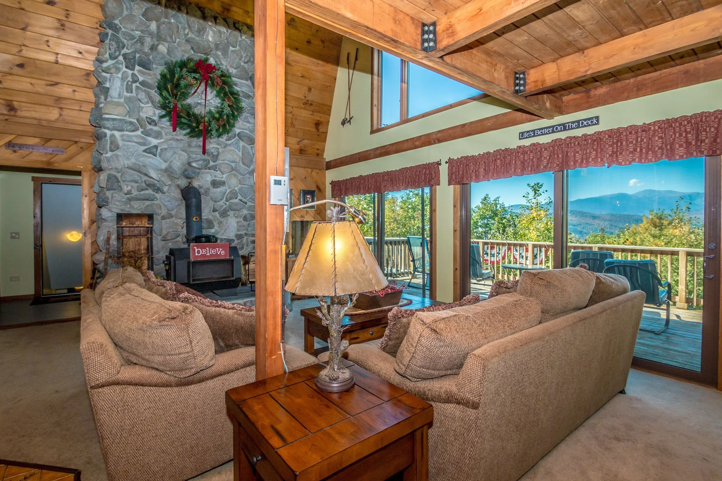 luxury mountain living room with stone hearth with woodstove, and incredible mountain views of the White Mountains in NH