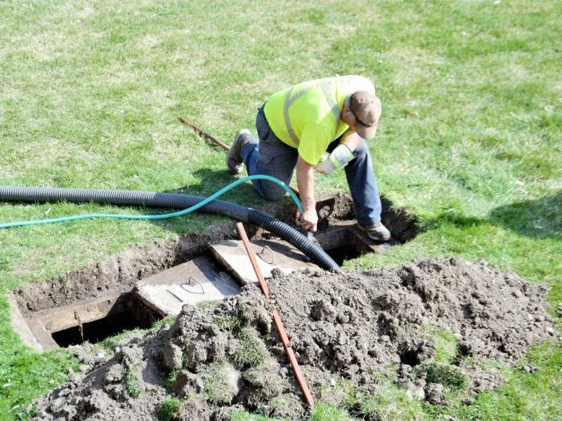 man knealing down to do a septic inspection