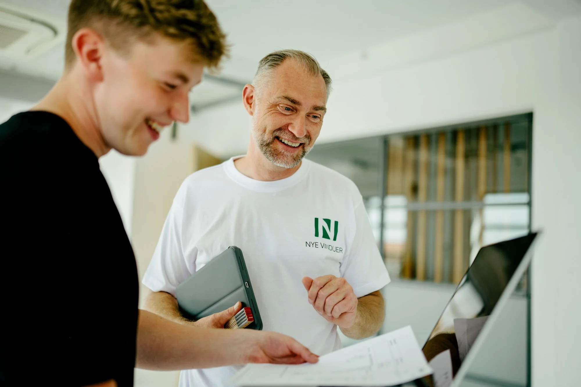 to mænd smiler og kigger på computeren