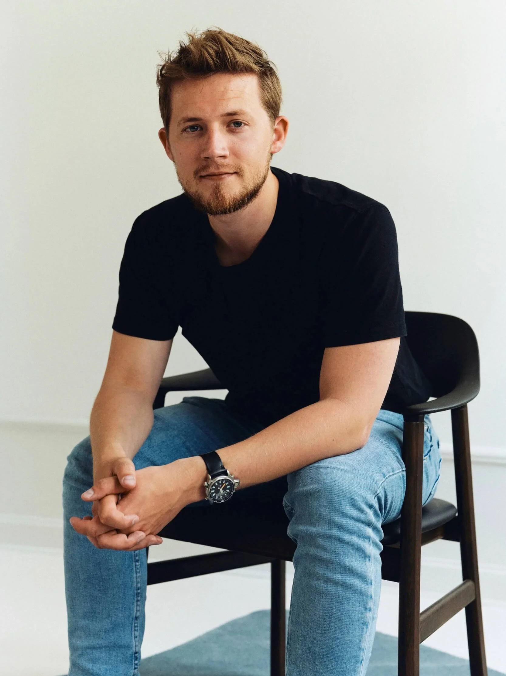 Portræt af mand på stol iført blå jeans og sort t-shirt