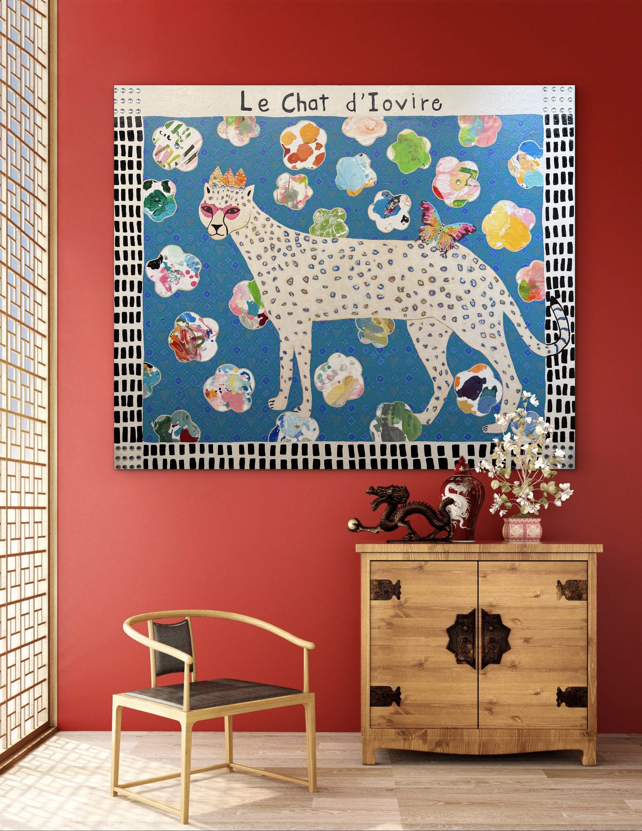In-room mockup of Le Chat d’Ivoire, a 60x72 mixed media painting of a crowned white spotted cat on a blue patterned background with colorful shapes and a butterfly.