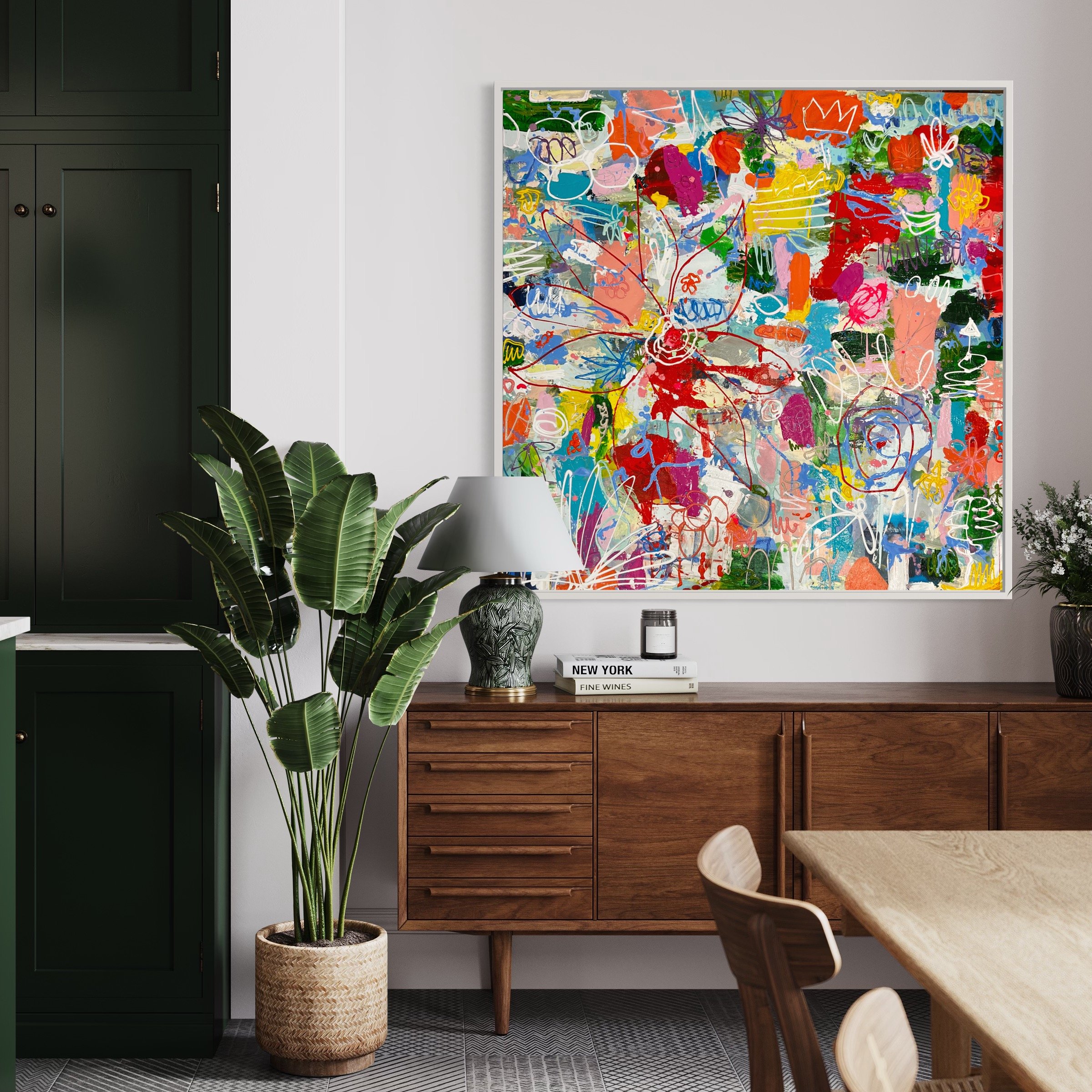 48x48 mixed media abstract painting with vibrant layered marks in red, blue, green, pink, and orange, framed above a wooden sideboard.