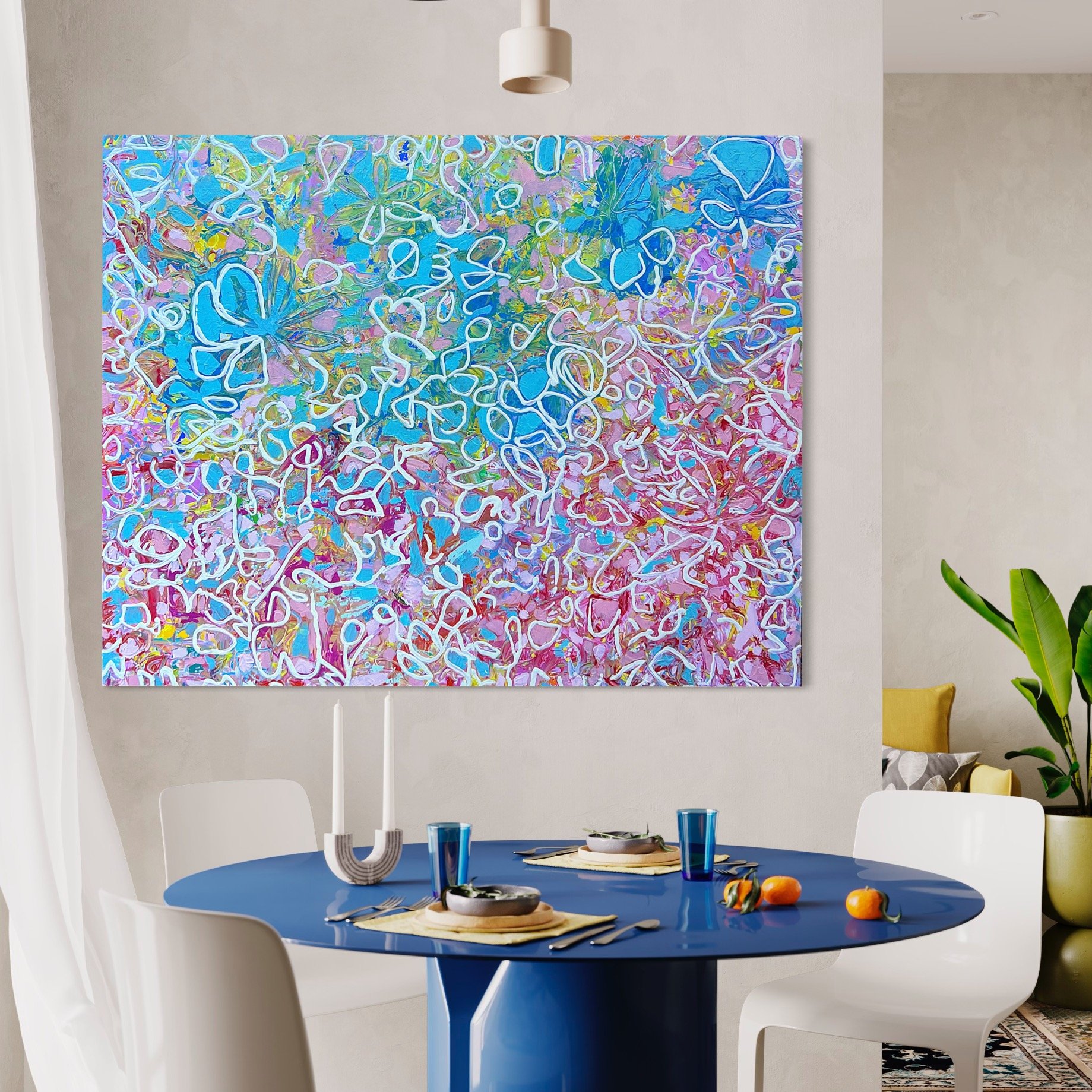 A dining room with a blue round table set with placemats, bowls, and glasses. There are four white chairs around the table. A modern white pendant light hangs above. A large abstract painting with colorful swirls is on the wall behind the table. Ther