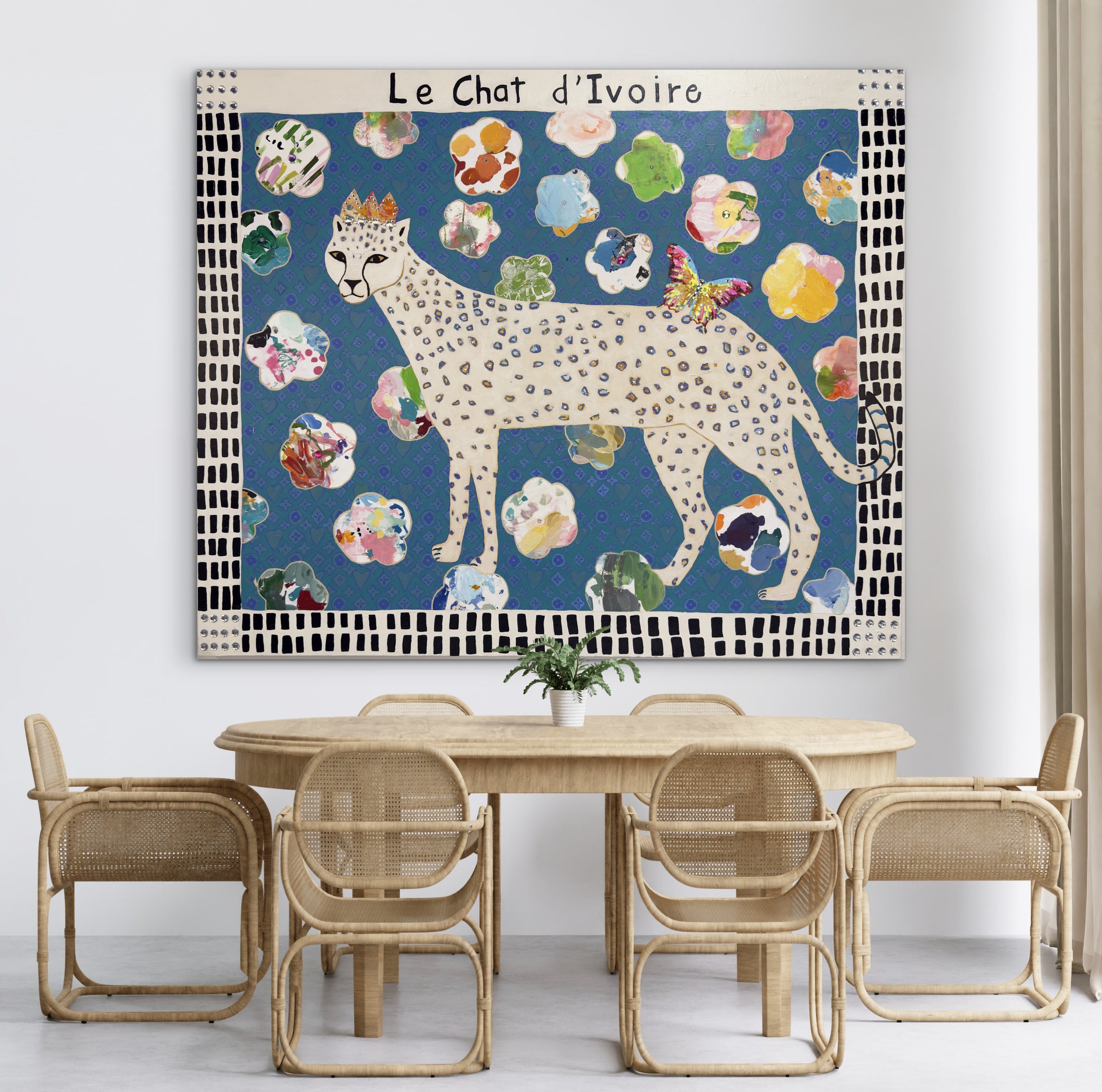 A wooden dining table with six matching rattan chairs in a room with white walls and a modern art piece titled "Le Chat d'Ivoire" on the wall.