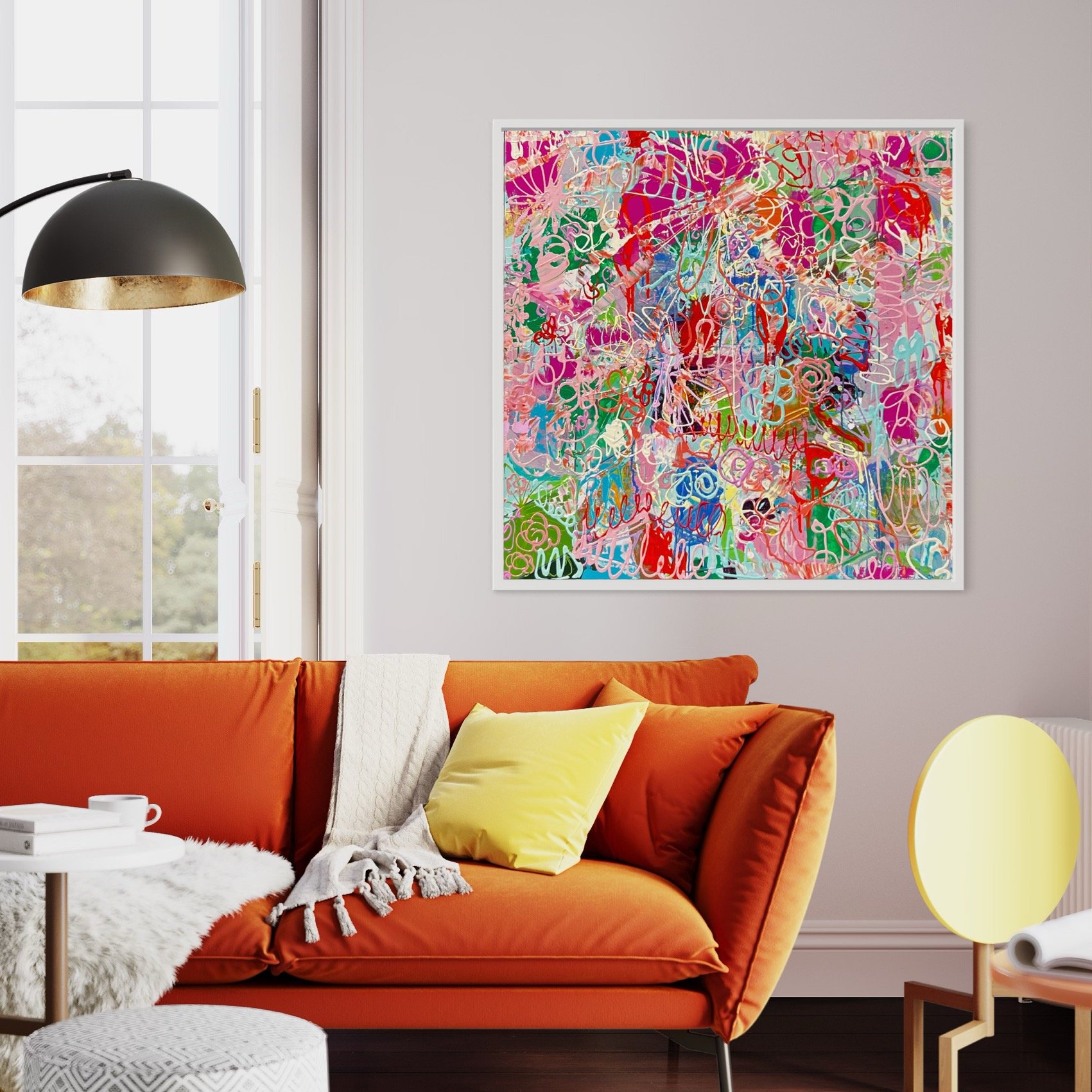 36x36 abstract painting with layered pink, green, red, and blue marks in a white frame above an orange sofa in a bright living room.