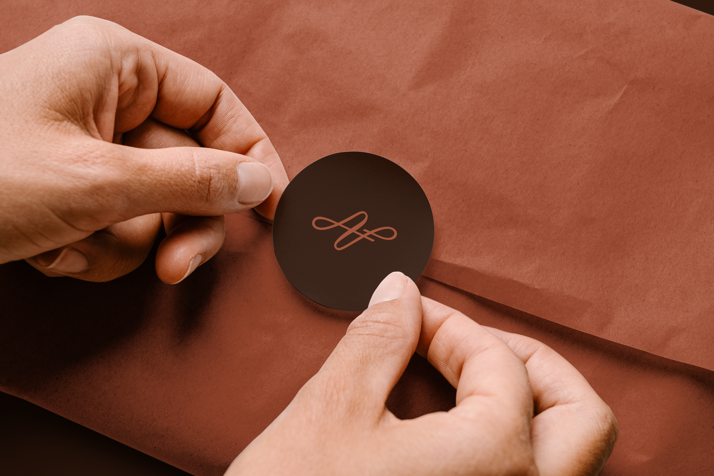 Close-up of hands applying a circular black sticker with a minimalist pink infinity symbol on skin.