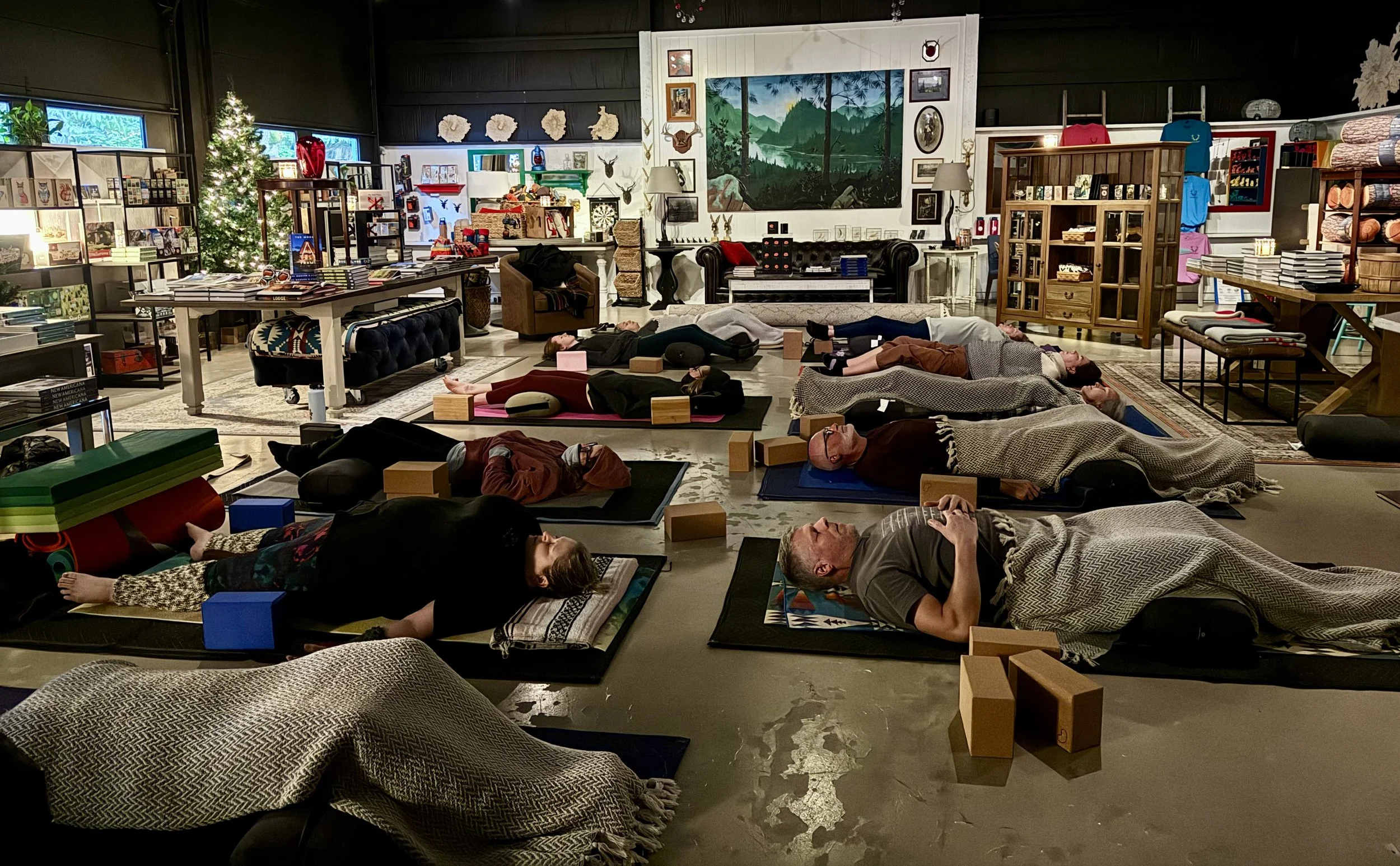 yoga students in savasana with blankets and props surrounding the mats