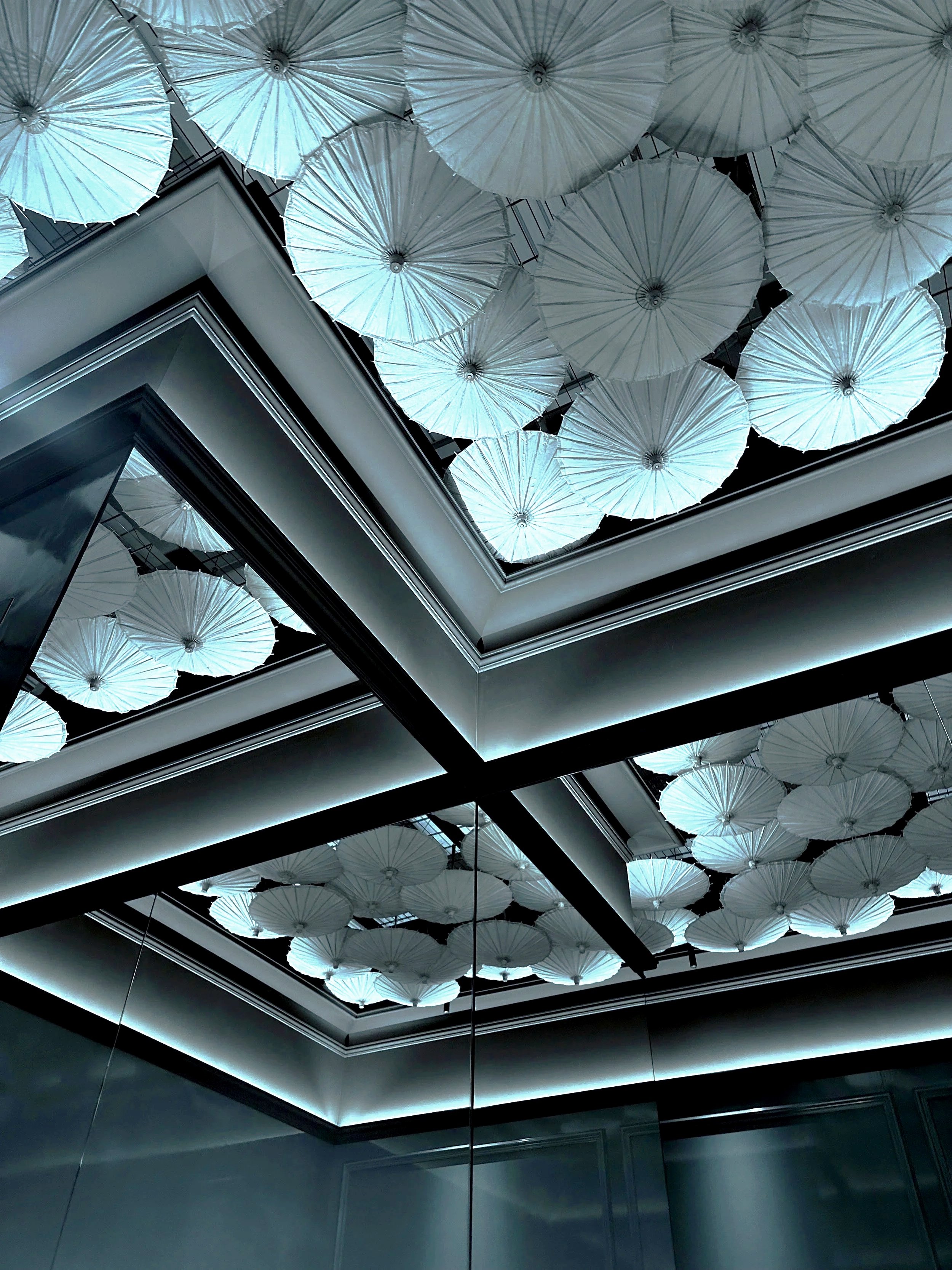 Ceiling decorated with numerous white umbrellas illuminated with soft lighting.