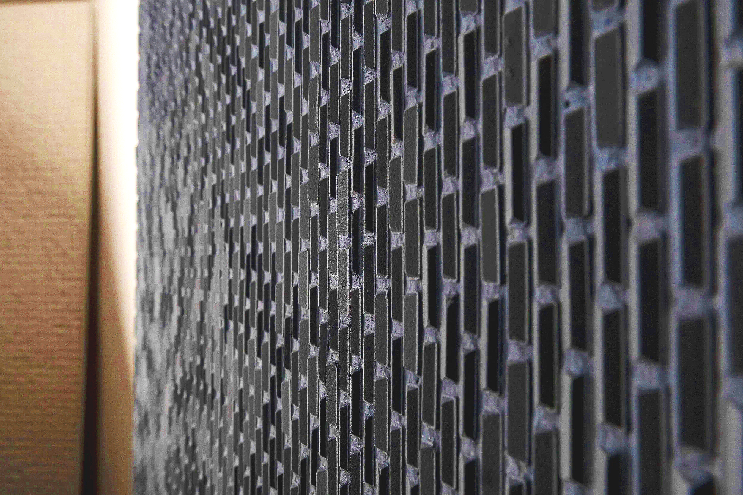 Close-up of a black metal or plastic vent or grille with a hexagonal honeycomb pattern.