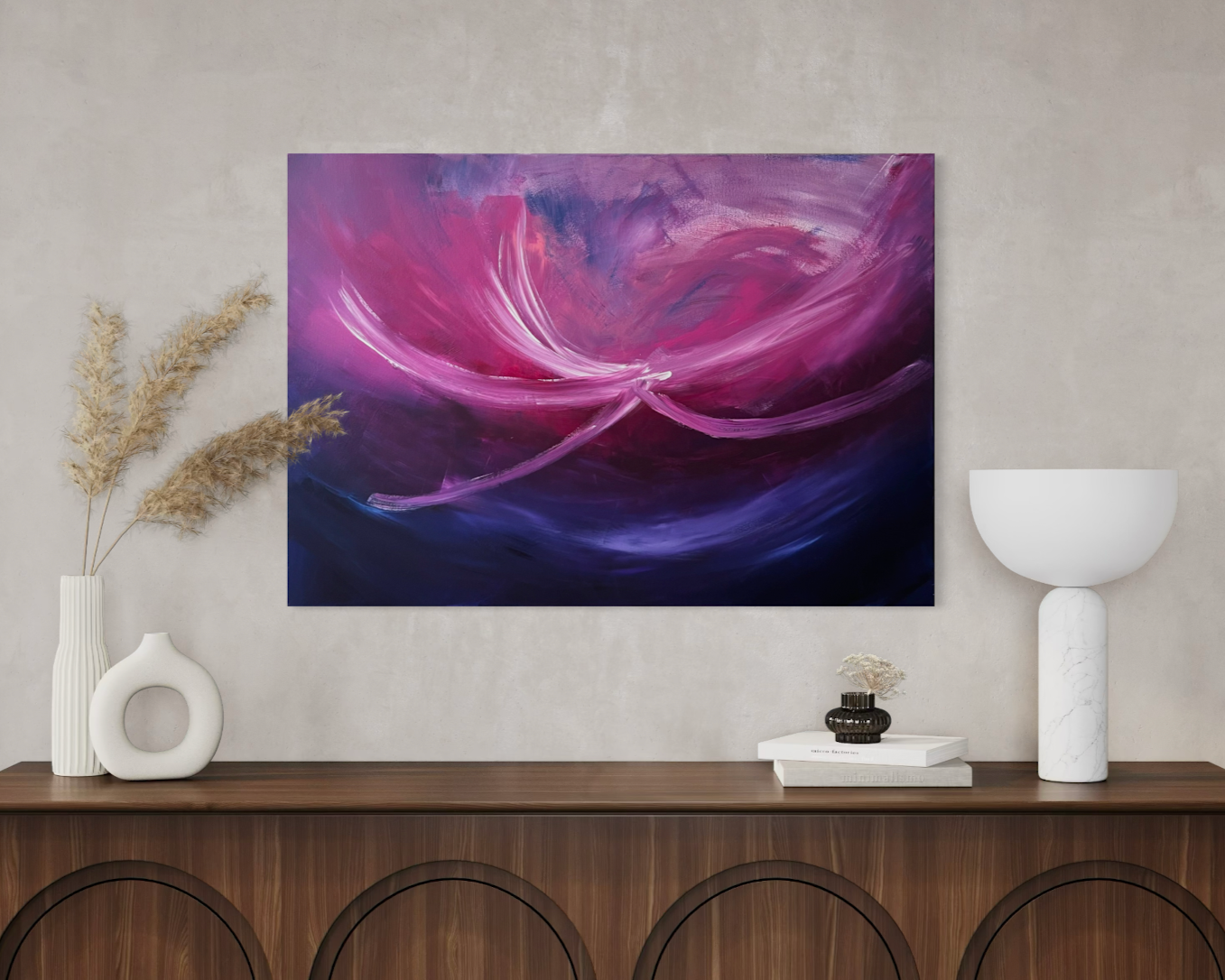 Ein abstraktes Gemälde in Pink- und Lilatönen an einer weißen Wand, auf einer Holzkonsole mit Vasen und Dekorationsstücken