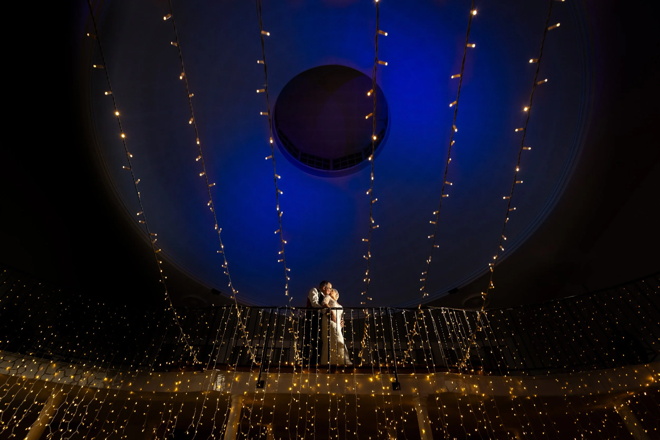 Newlywed couple at Kings Chapel in Amersham at night with the dome lit blue and fairy lights creating a magical setting. 