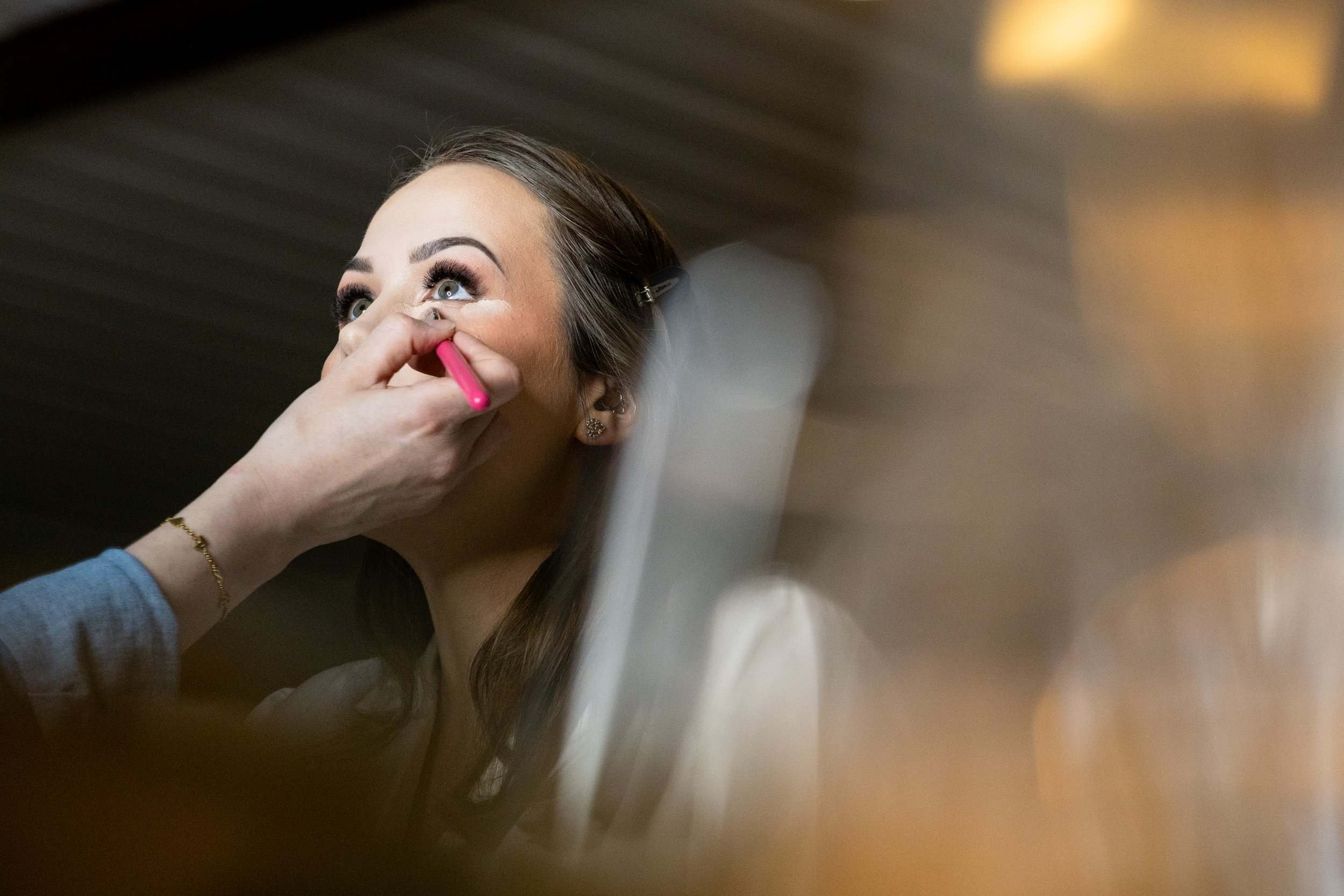 Makeup artist applying makeup to a bride's face.