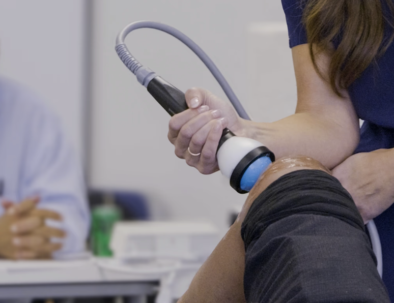 woman applying stemwave non invasive therapy  on patients knee