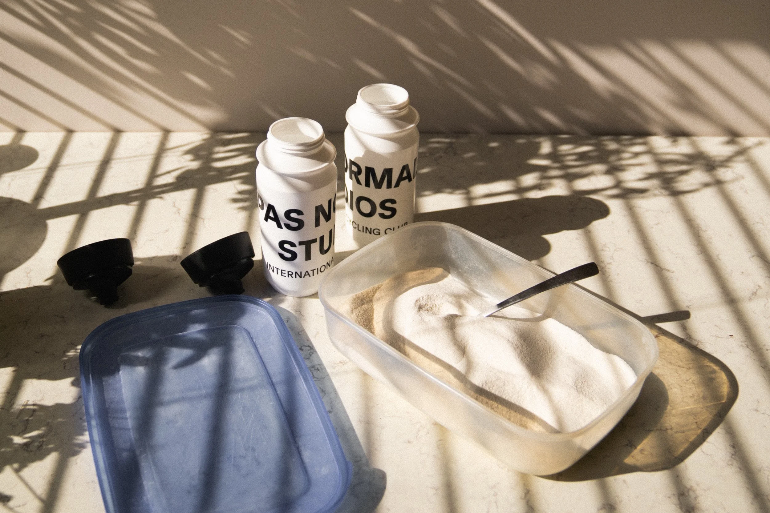 Homemade sports drink mix stored in an airtight container alongside cycling bottles, ready to be mixed with water before a ride.