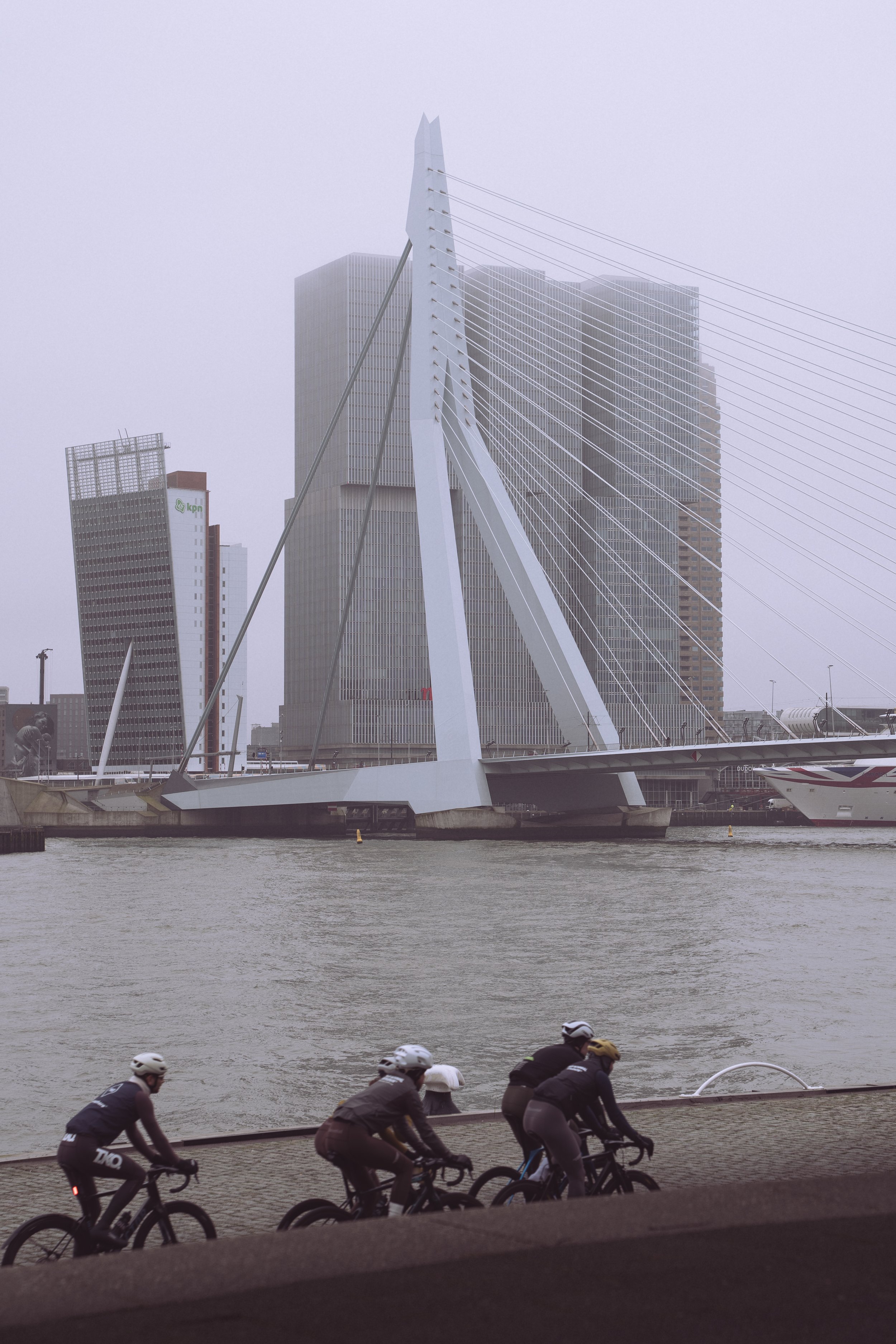 Road cycling along the Maas river with views of Rotterdam’s modern skyline and Erasmusbrug riverside bike path.