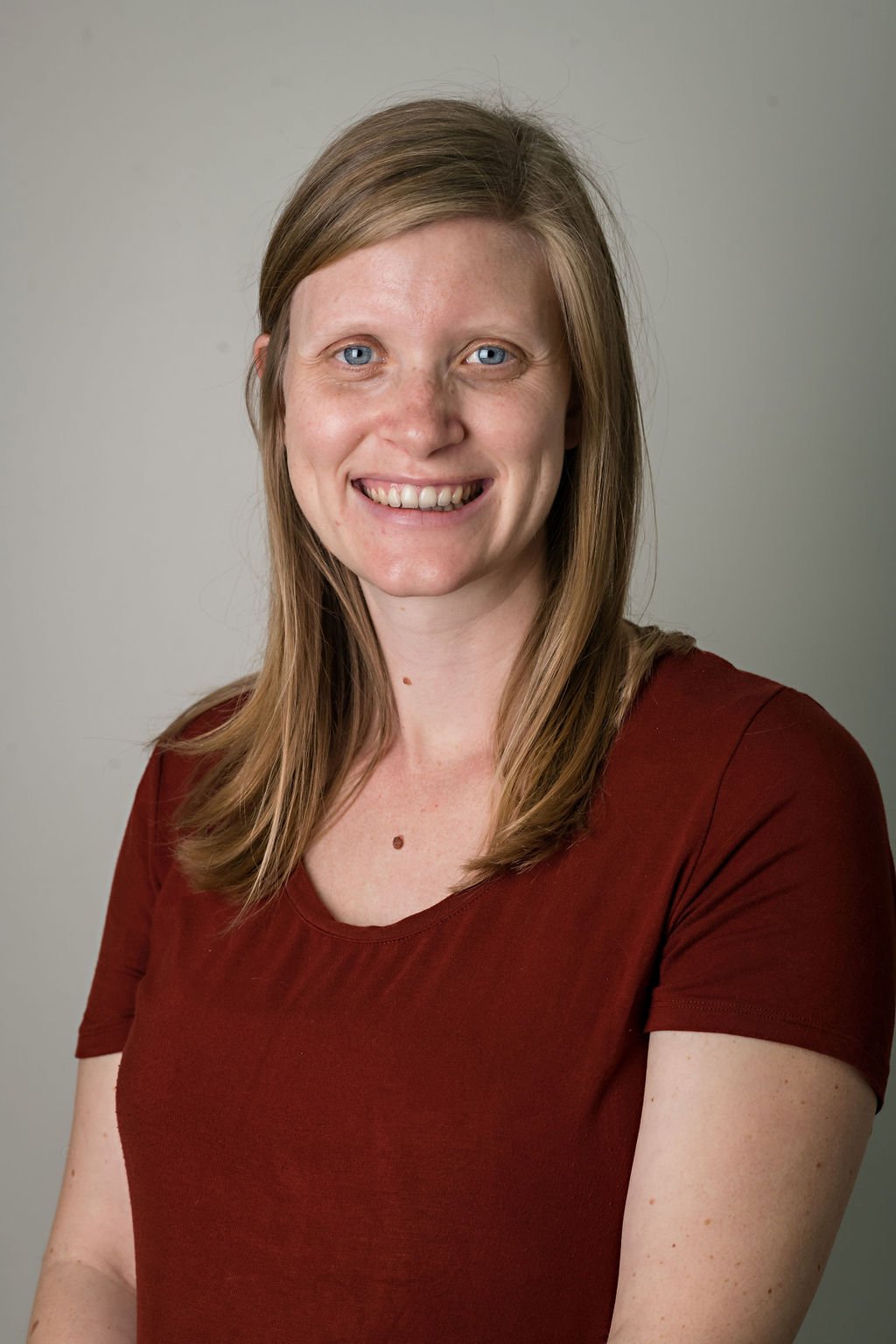 Pelvic Physiotherapist Jessica Tomlin poses for a professional photograph against the wall of the clinic.