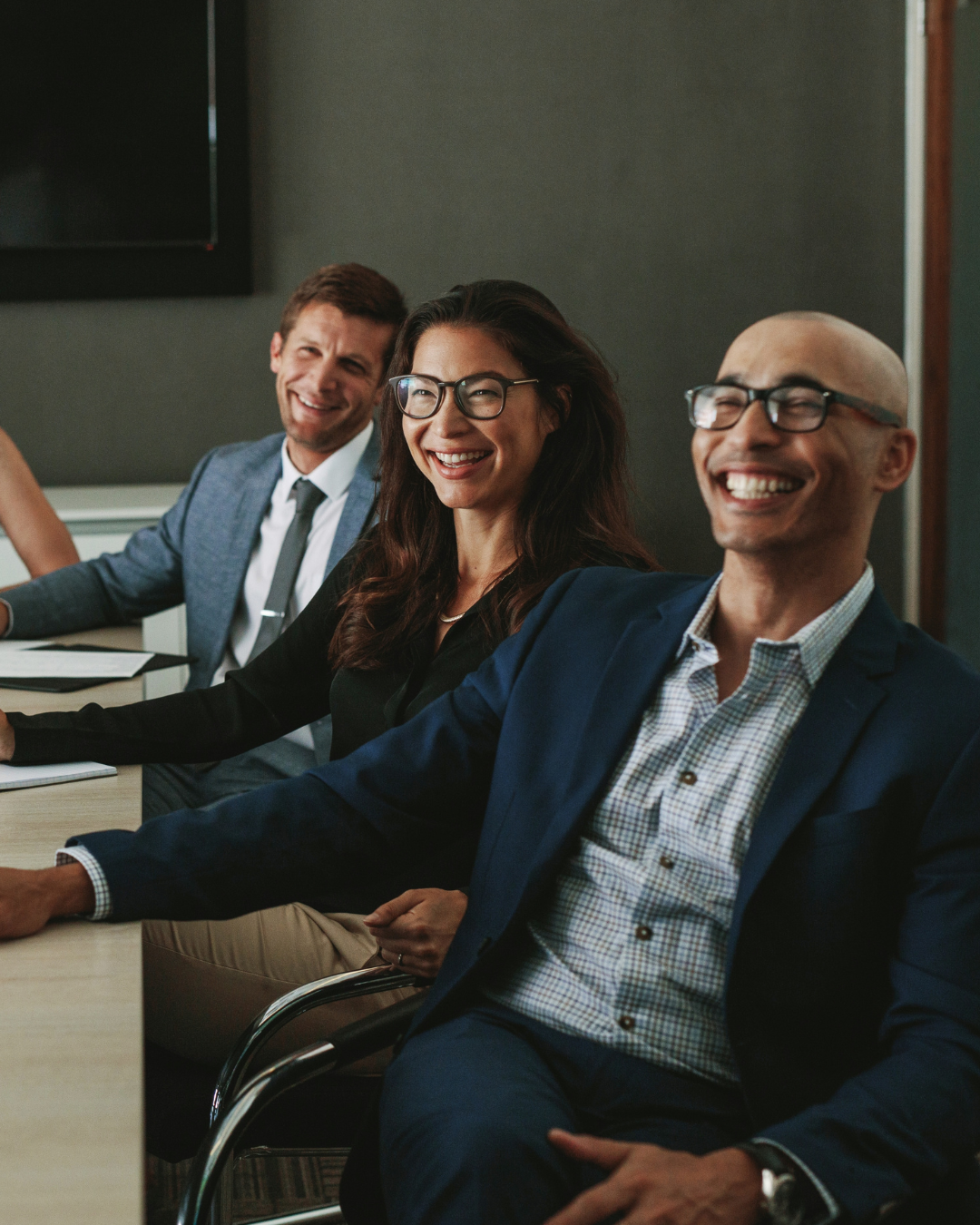 Adults in a meeting and smiling at a speaker.