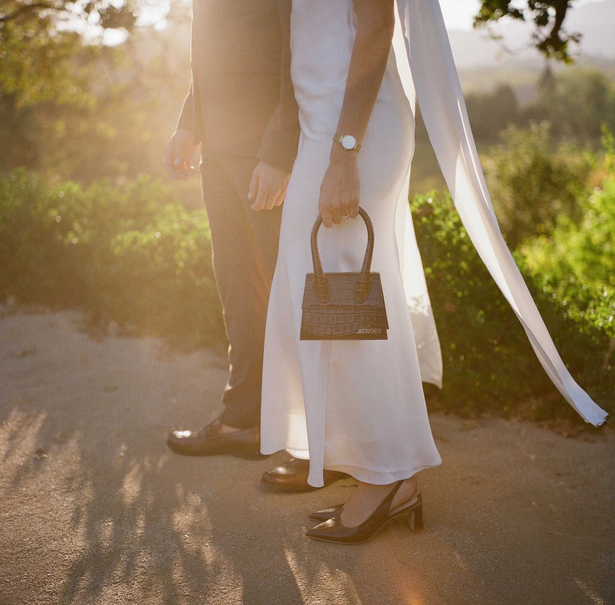 Bride holding Jacquemus bag with cape veil in golden hour light at Stonepine Estate, couple walking the grounds, film wedding photography by Radostina Boseva Carmel Valley