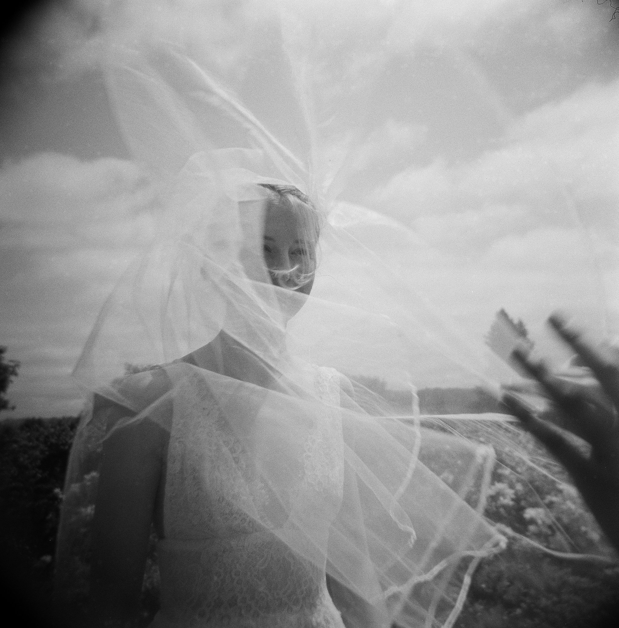 Bride's veil caught in the wind above Napa Valley hills — film wedding photography by Radostina Boseva