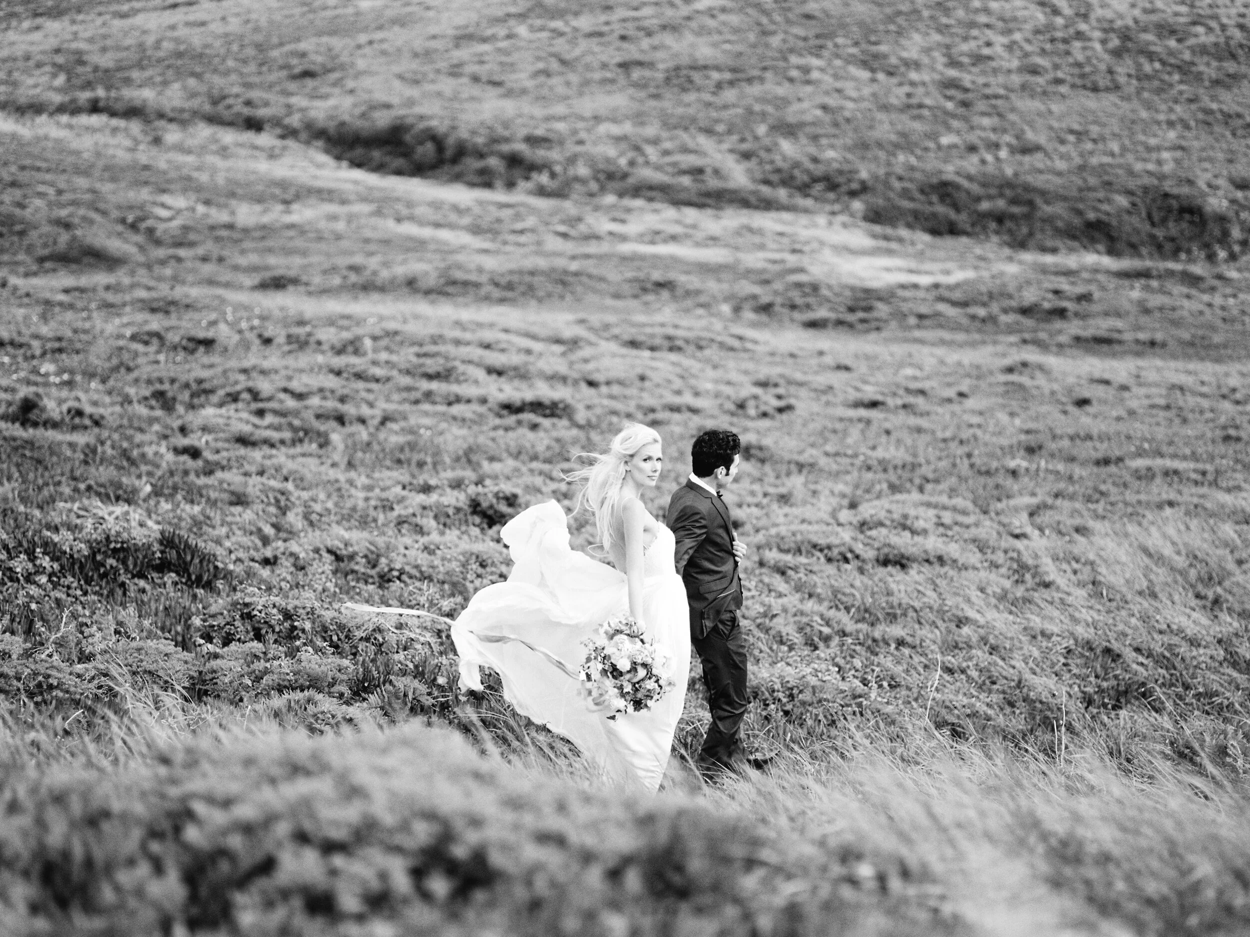 Bride and groom walking through open landscape in black and white — documentary film wedding photography, San Francisco