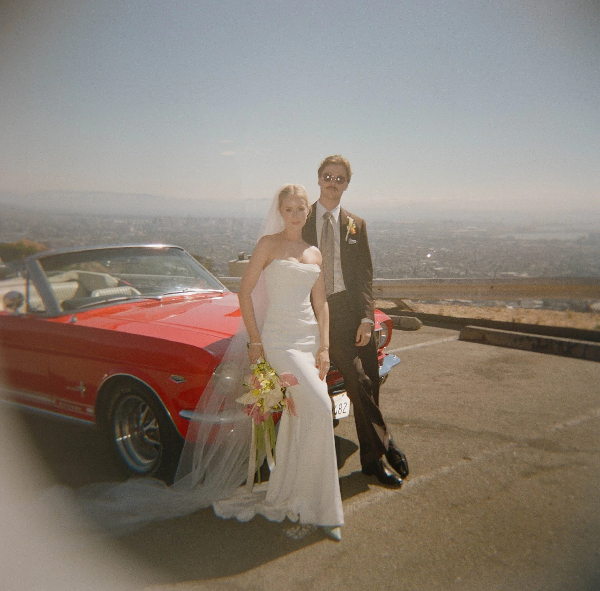 bride and groom beside a vintage red convertible overlooking a hazy bay area skyline · california elopement · documentary film photography by radostina boseva