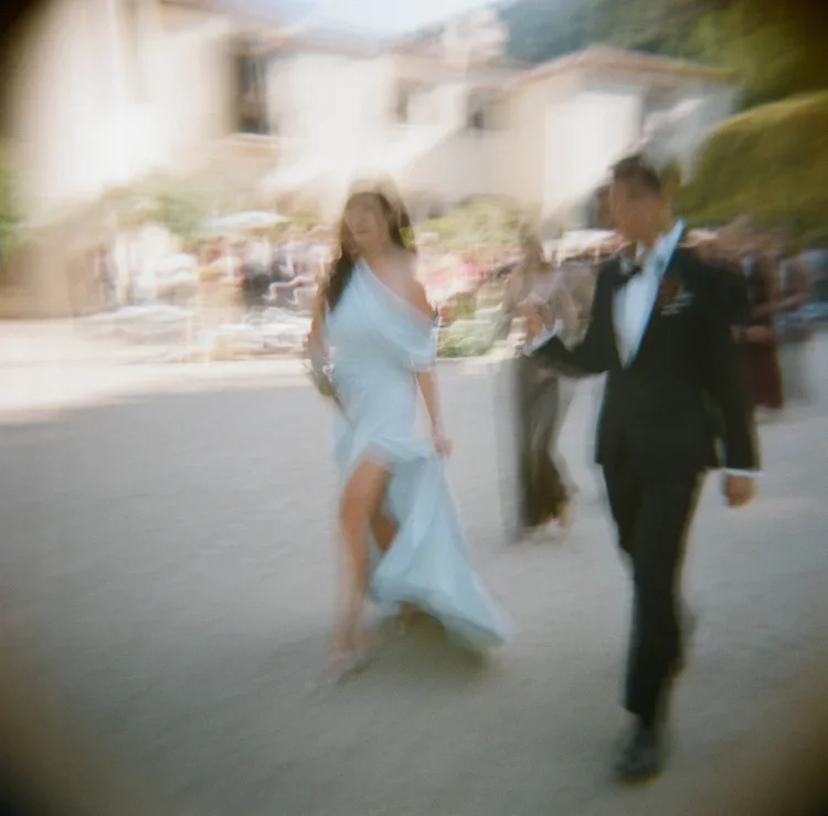 Bride and groom running through Italian village street, motion blur film photography, destination wedding photographer Italy