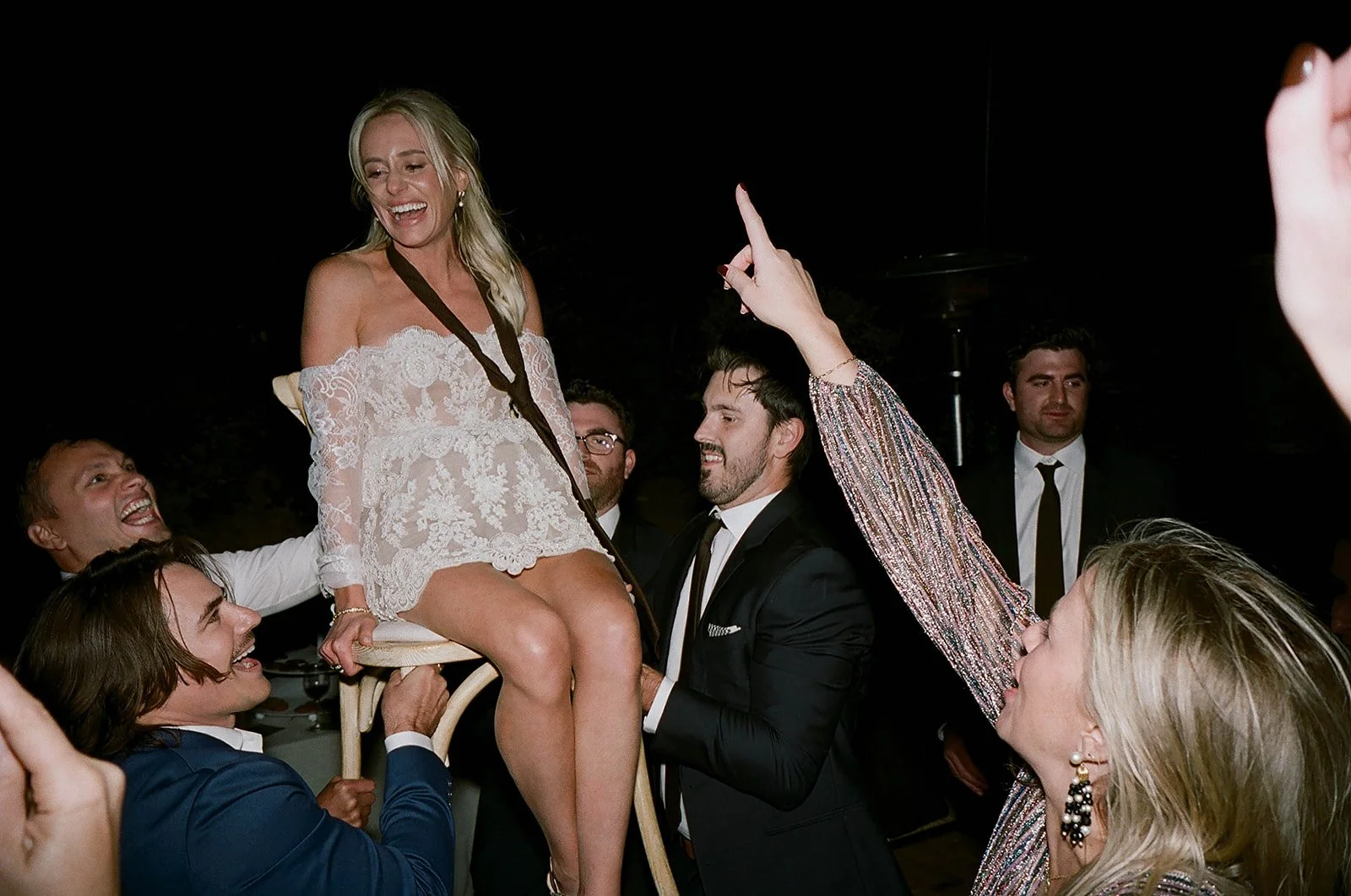 Bride lifted in chair during joyful wedding reception at night, documentary film photography, Big Sur wedding photographer California