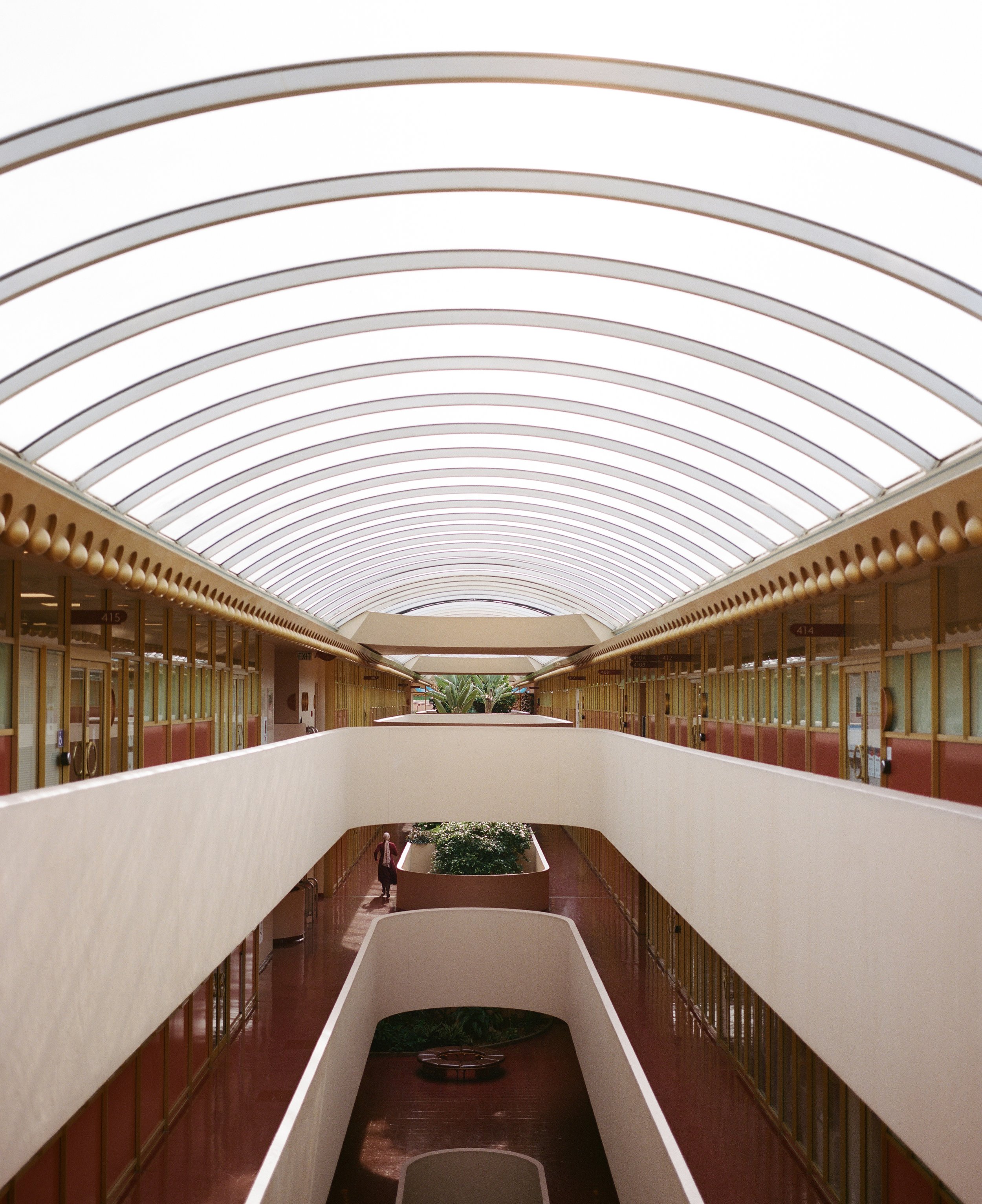 elevated skylight corridor with office doors and a figure walking · marin county civic center · documentary film photography by radostina boseva