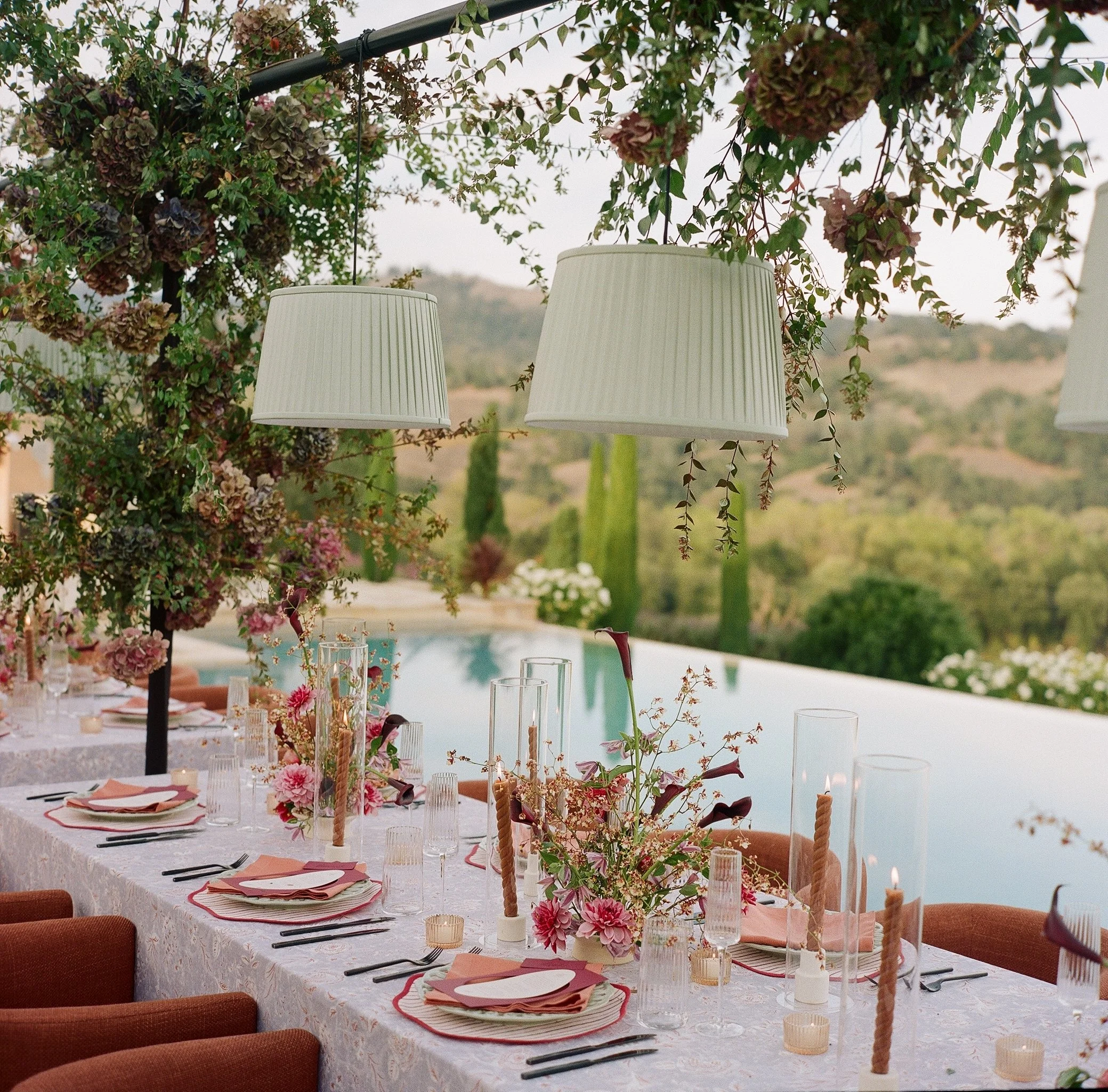 Outdoor wedding reception table with candles and floral arrangements overlooking vineyard landscape, film wedding photography