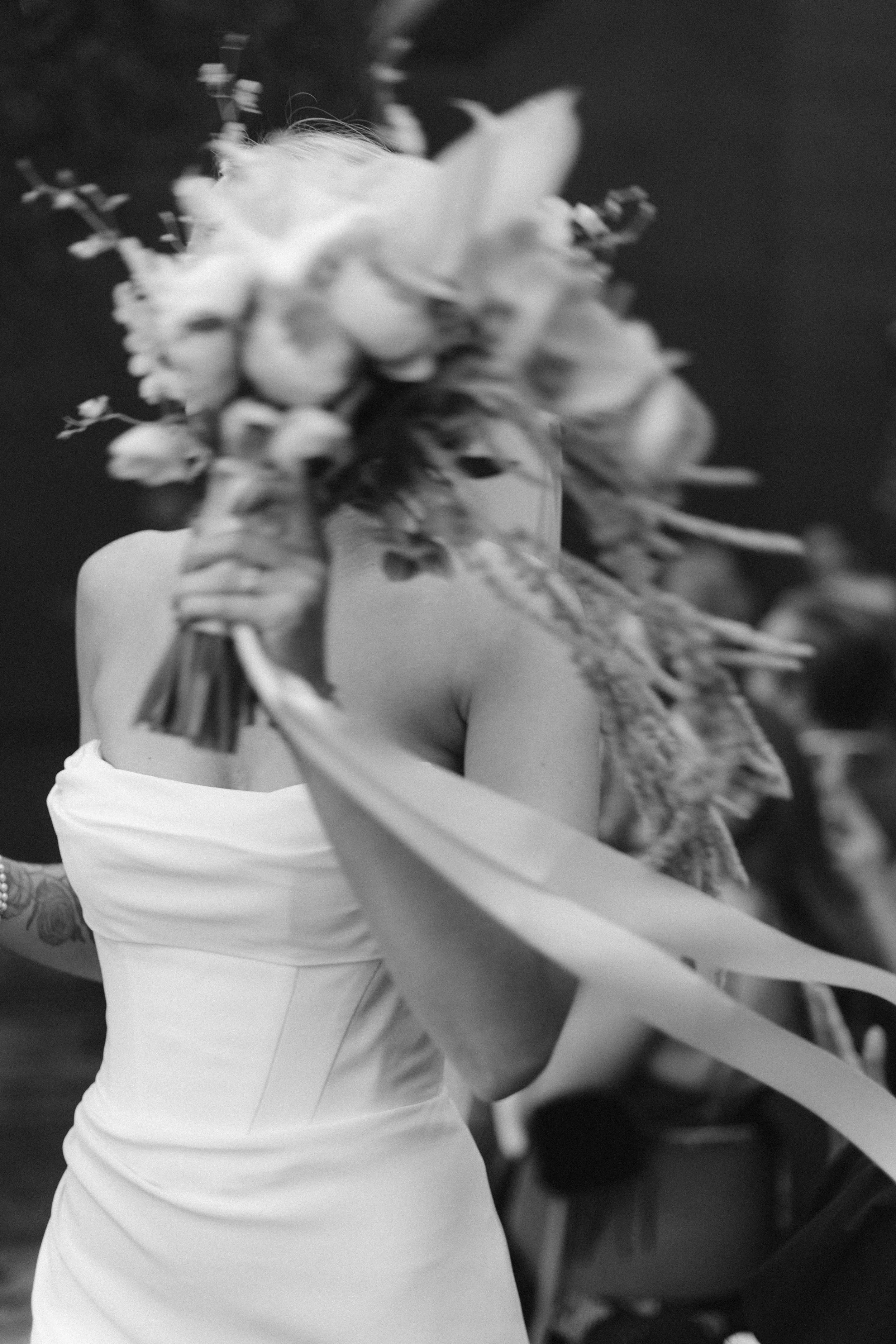 Candid documentary moment of bride with bouquet in wind — analogue film photography by Radostina Boseva