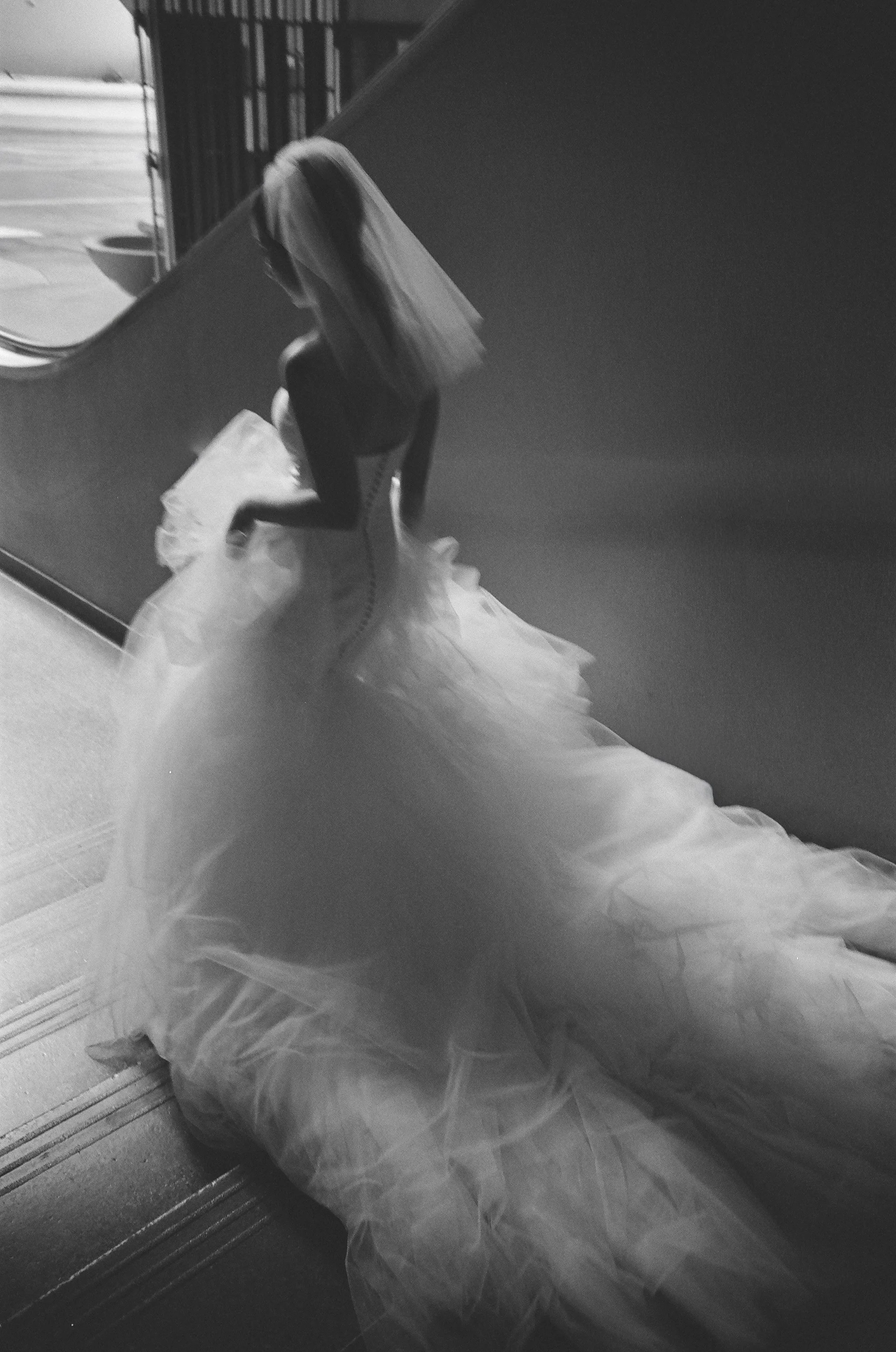 bride in a vintage maggie sottero gown with a full tulle skirt, captured in motion on the staircase · black and white documentary film photography by radostina boseva