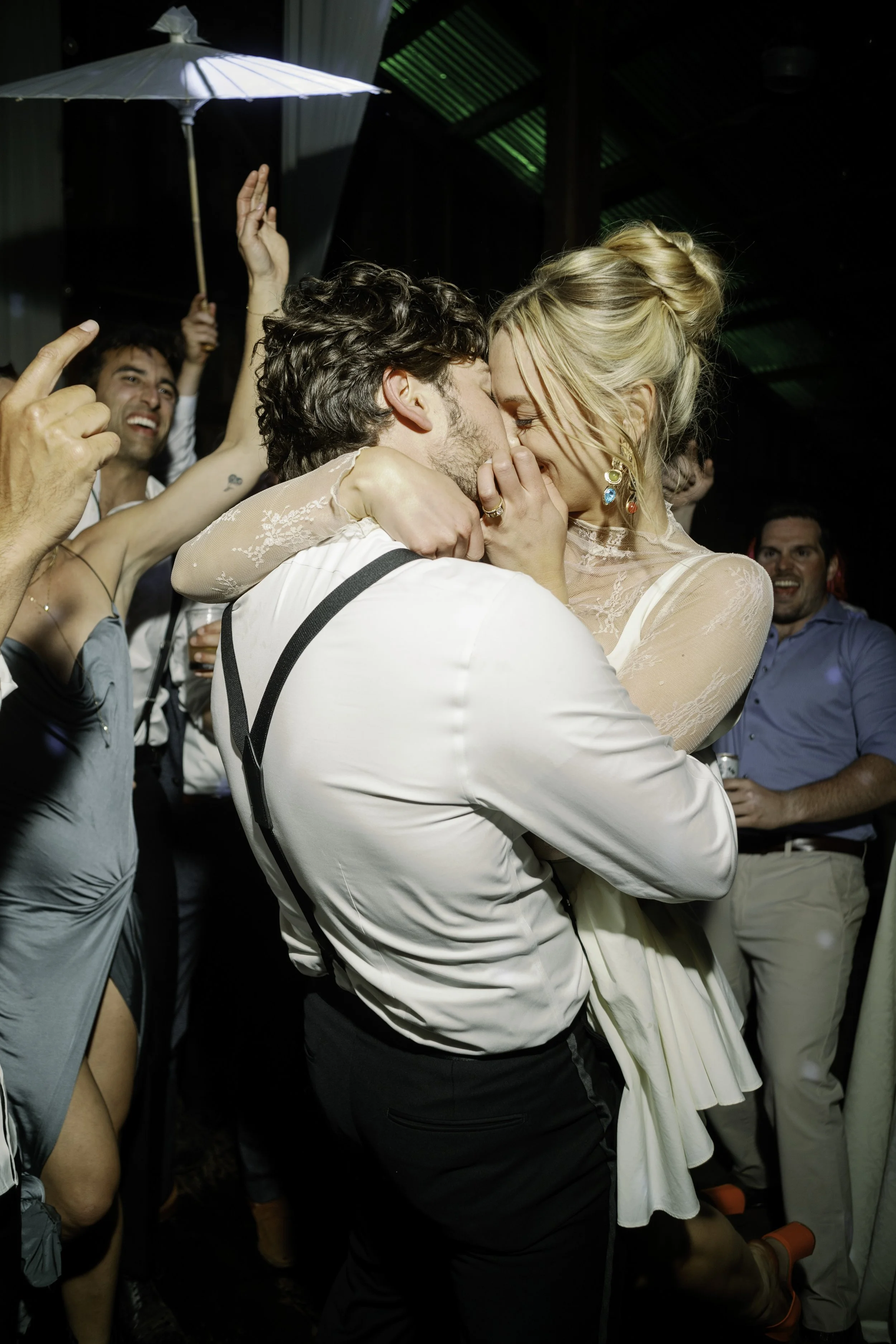 bride pulling the groom in for a kiss on the dance floor at a mendocino wedding, guests celebrating around them, direct flash on film