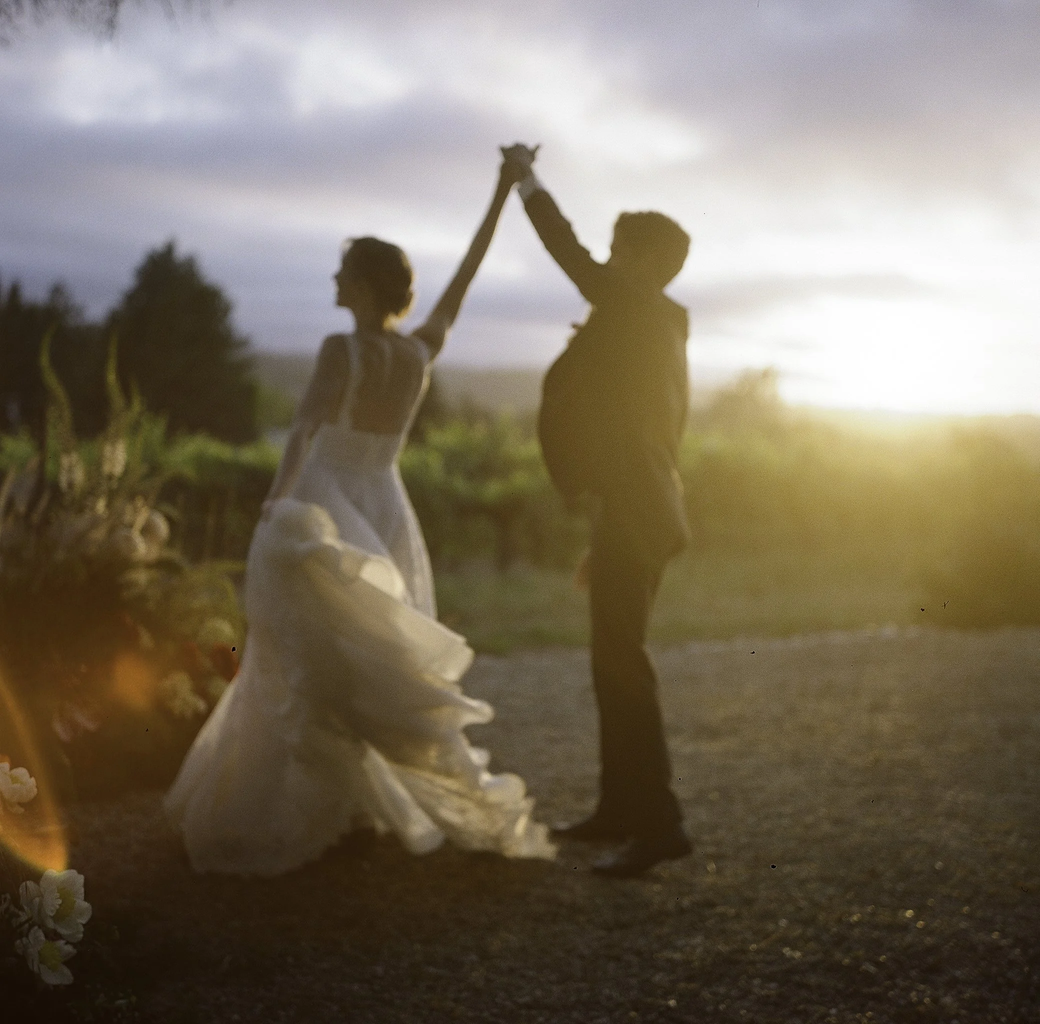 bride and groom dancing at golden hour sunset with coastal vineyard backdrop, big sur california — film wedding photography by Radostina Boseva