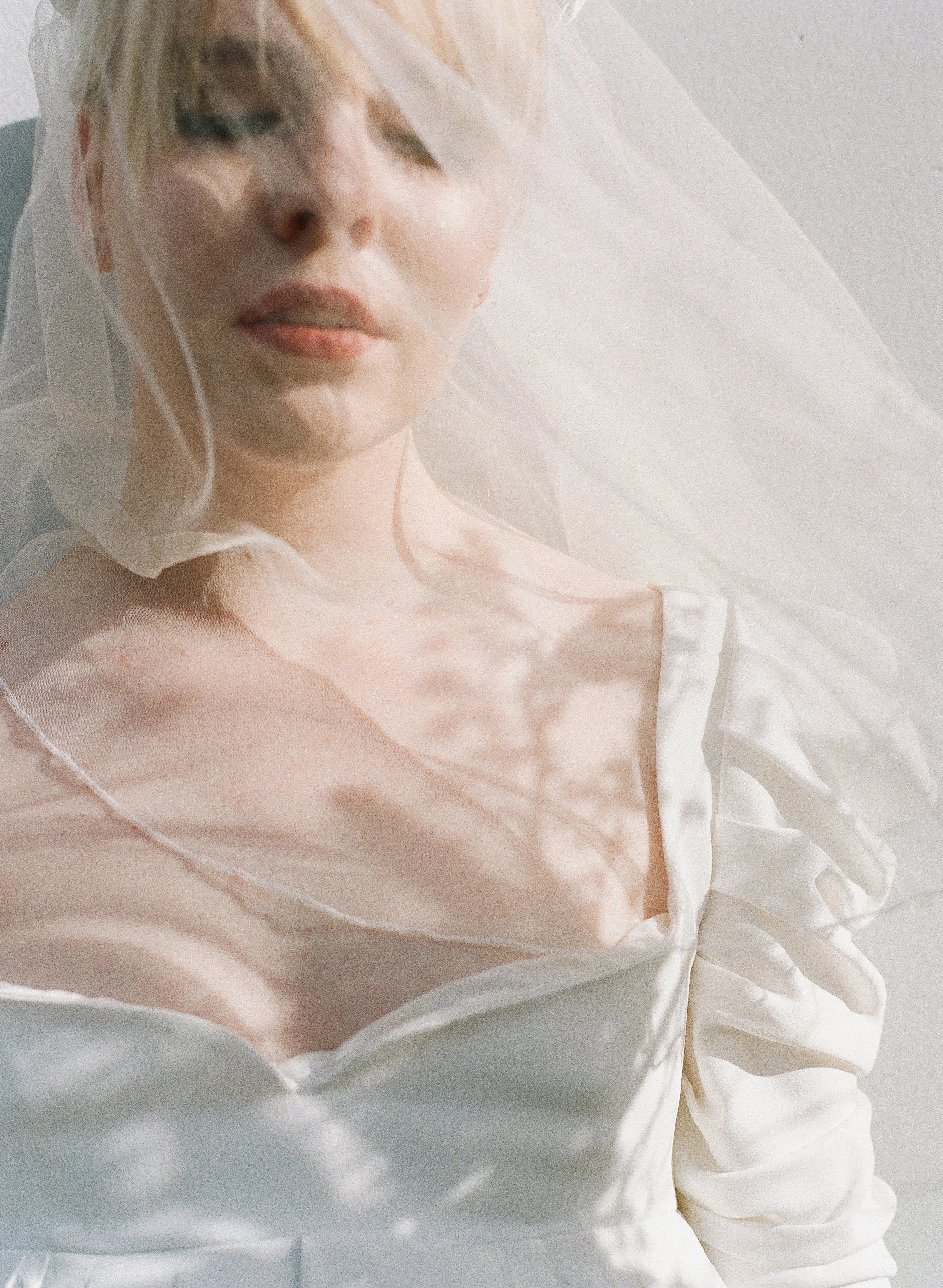 close portrait of a bride under her veil, eyes closed, dappled sunlight on film