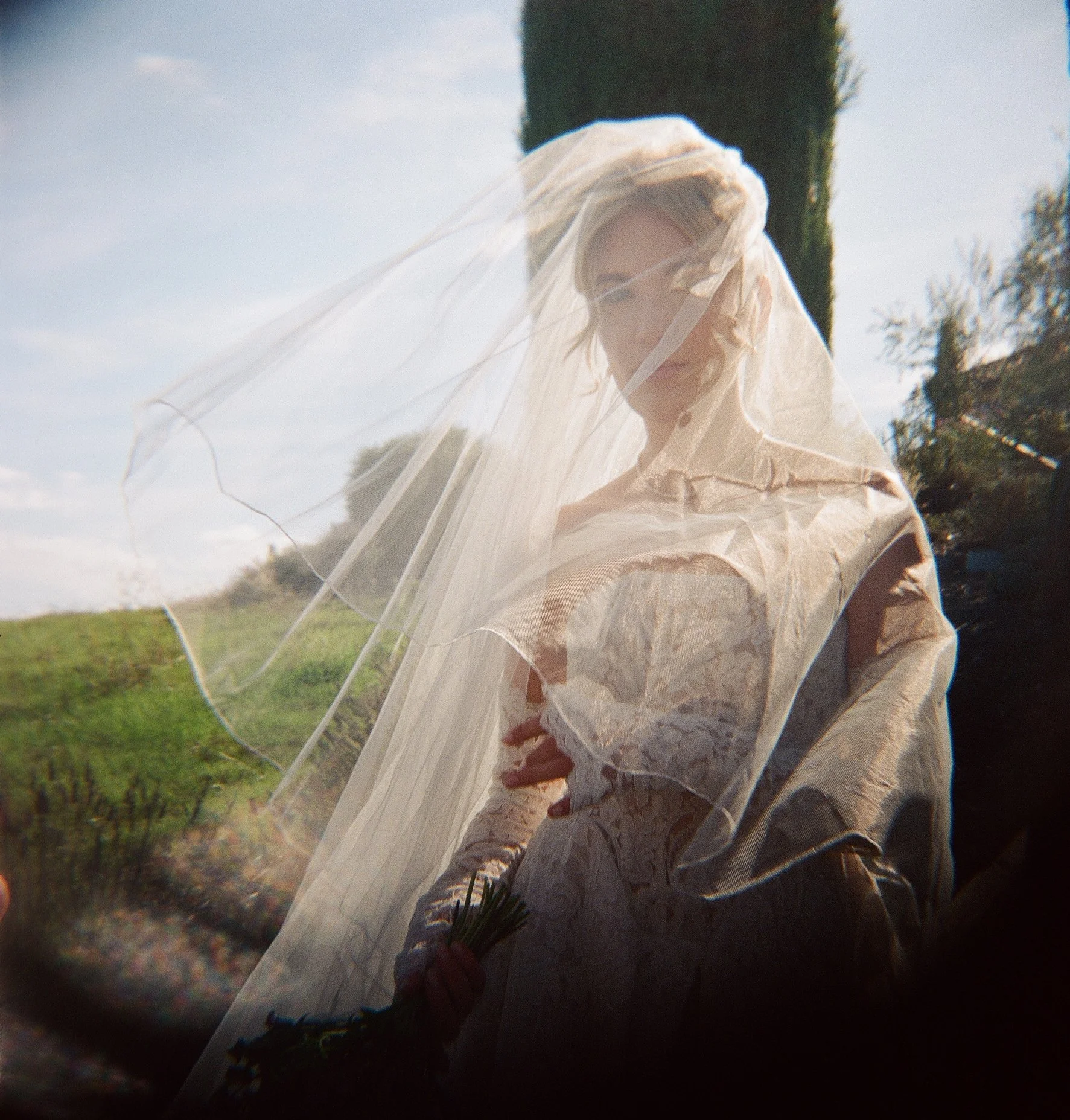 bride with veil caught in the wind holding wildflowers, mendocino northern california — film wedding photography by Radostina Boseva