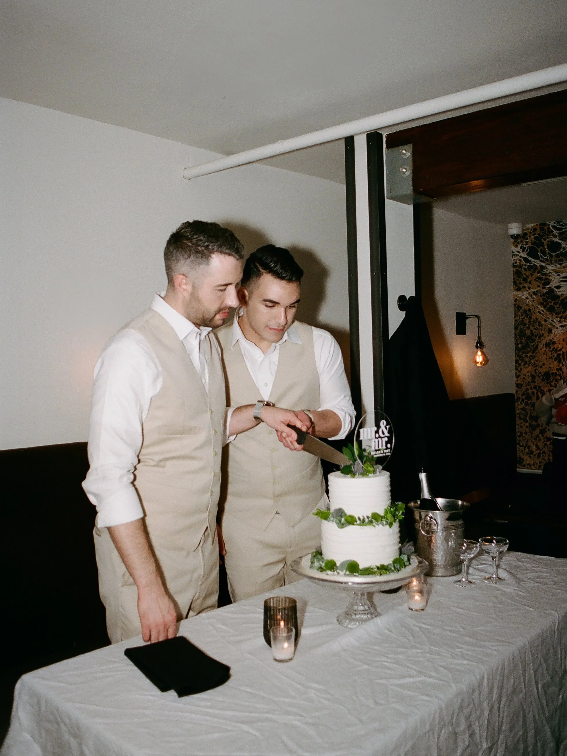 Two grooms cutting their wedding cake at a San Francisco reception, film photography by Radostina Boseva