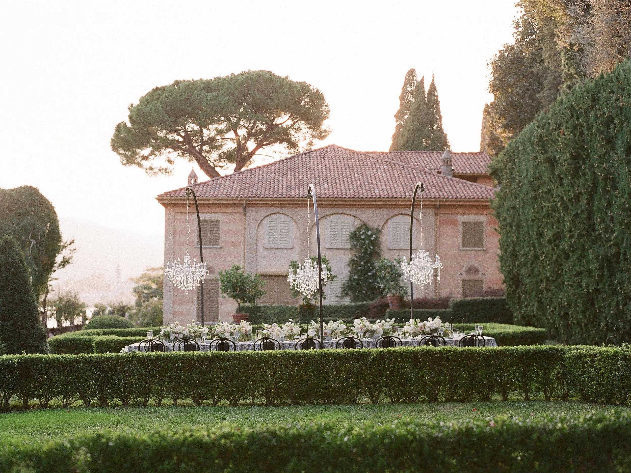 Outdoor wedding ceremony setup with crystal chandeliers in formal garden of Lake Como villa, destination wedding photographer Italy