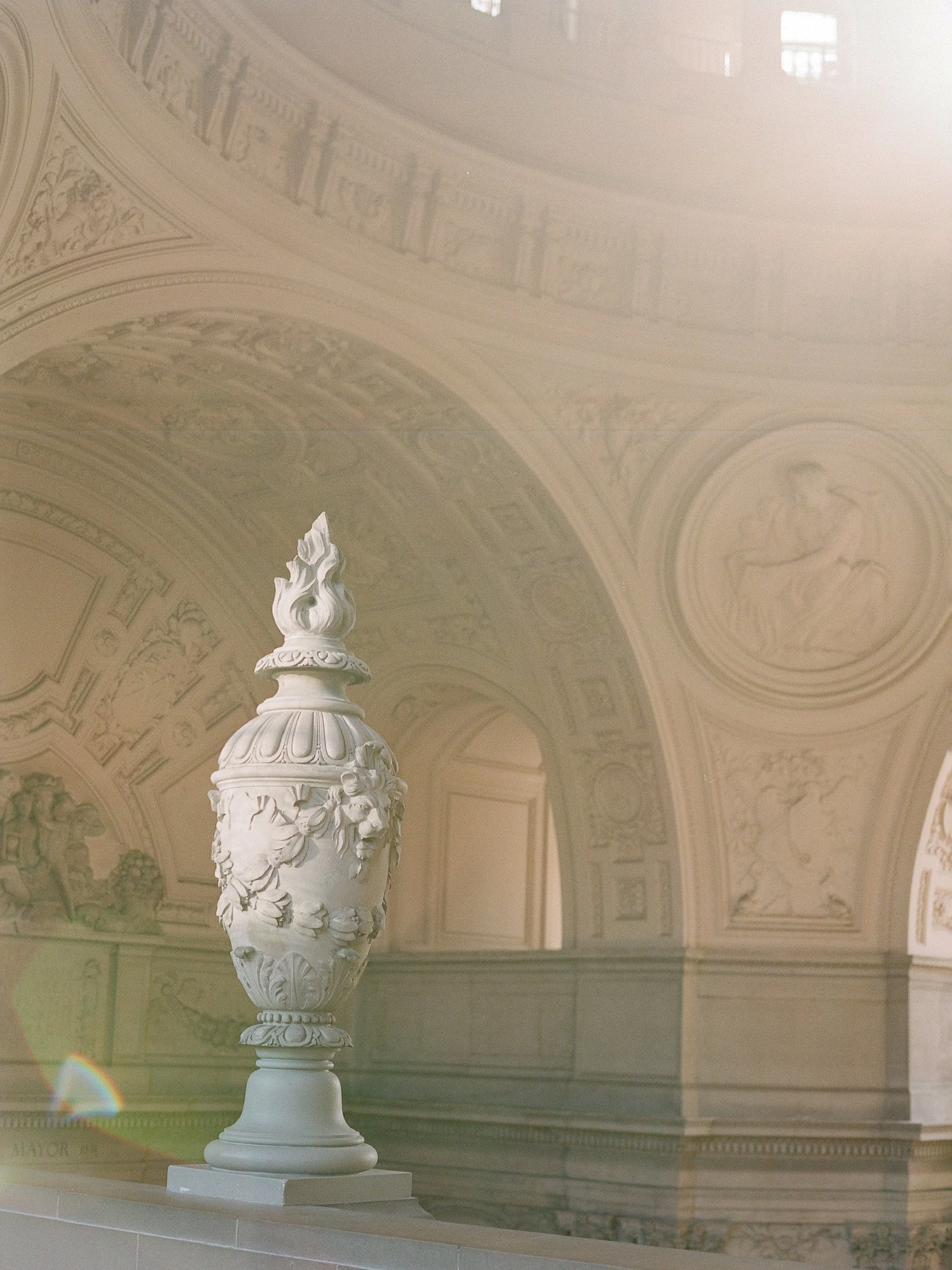 San Francisco City Hall ornate stone urn with flame finial in arched hallway, sunflare on film by Radostina Boseva