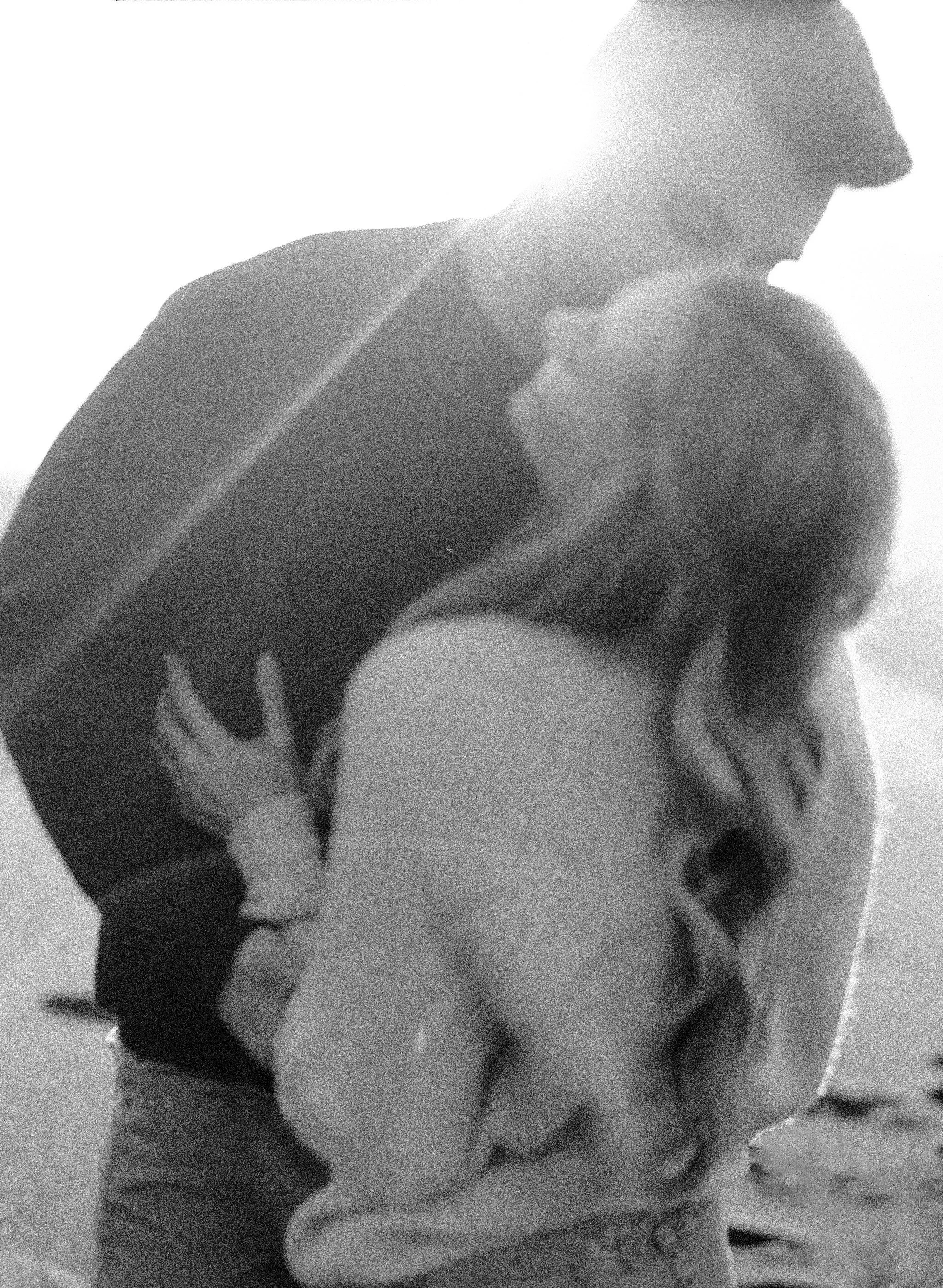 Intimate black and white film portrait of couple embracing, backlit, Mendocino wedding photography