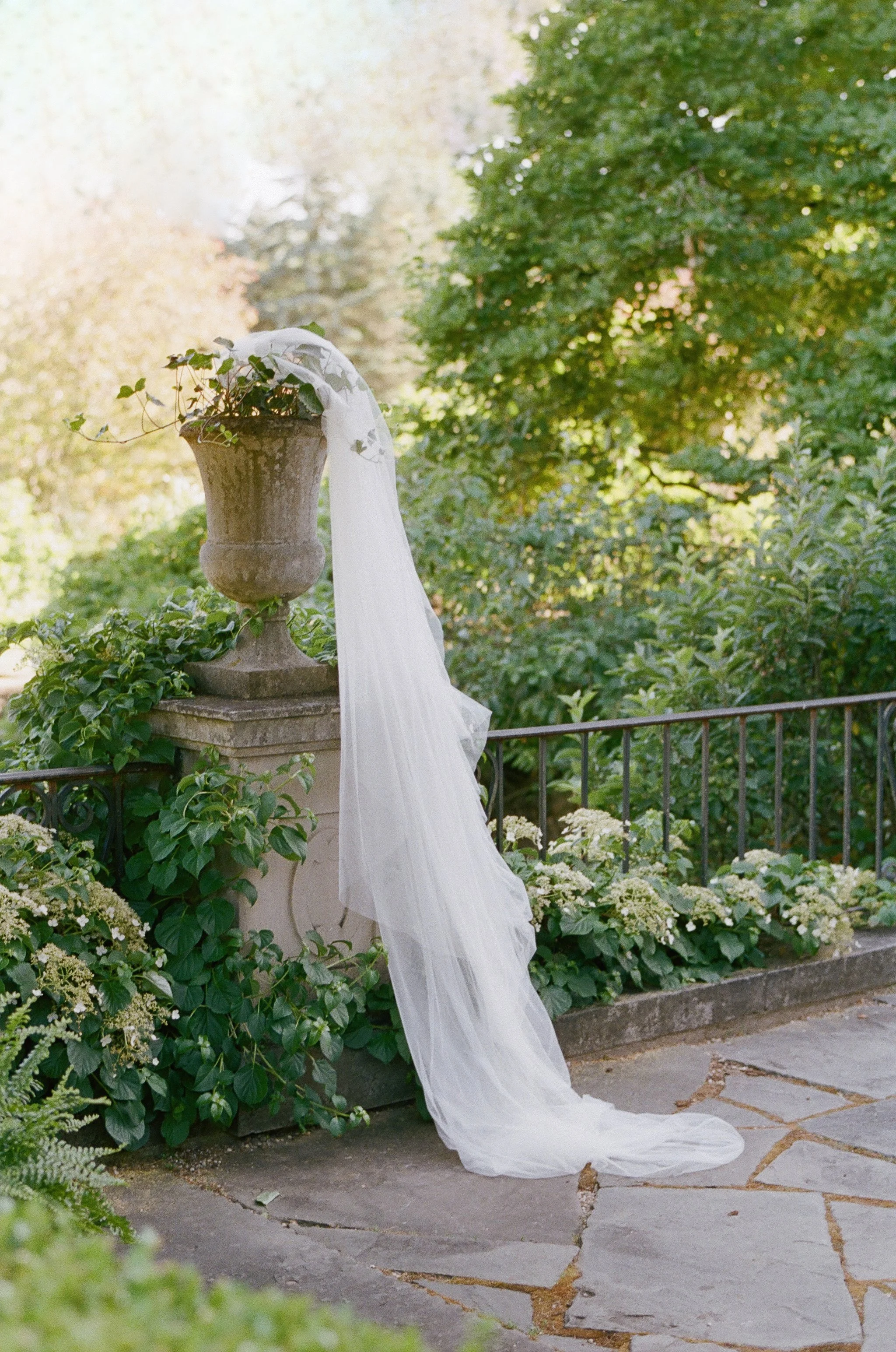 Bride in veil beside a stone urn in a lush garden — film wedding photography, San Francisco