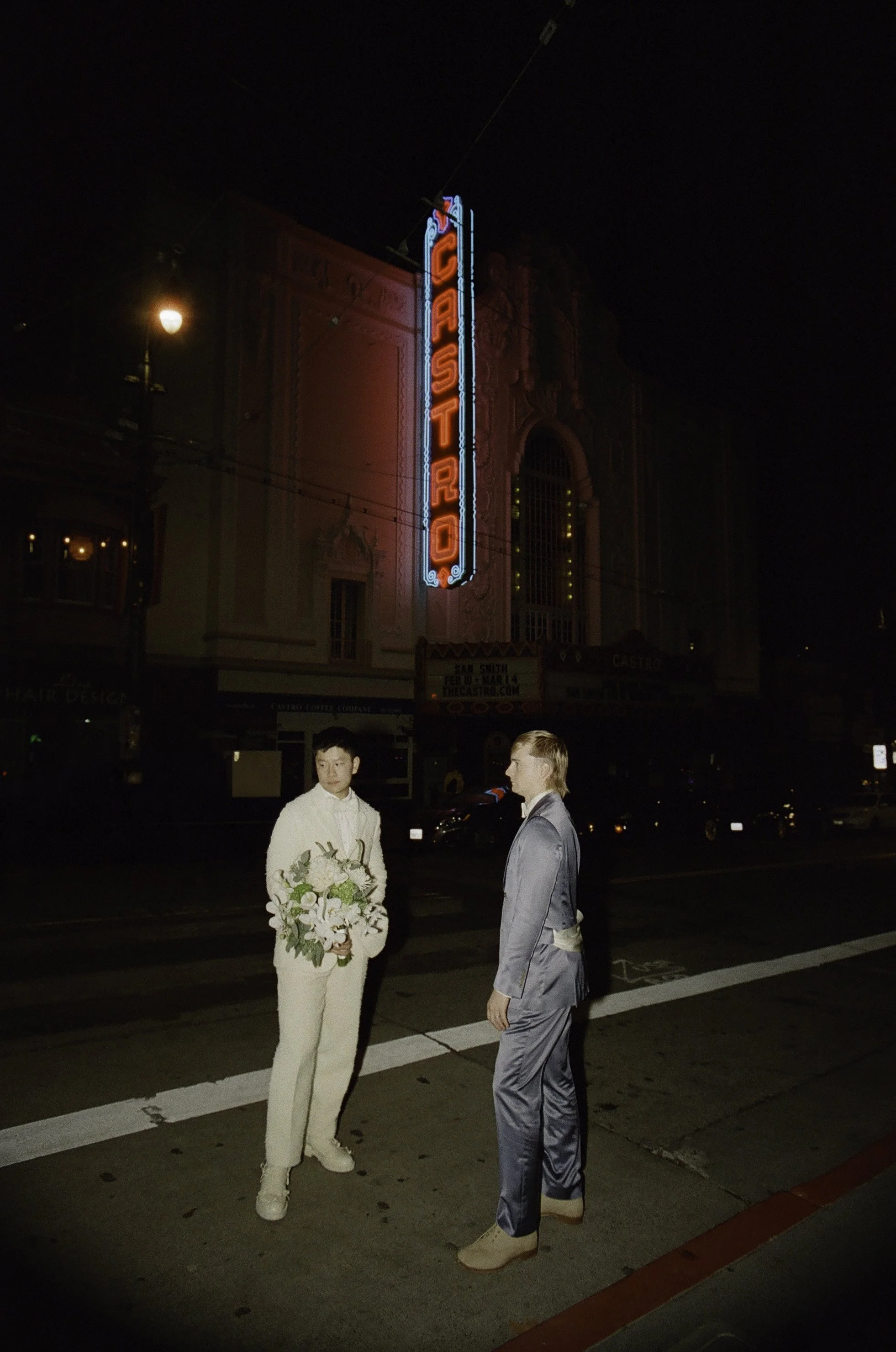 Two grooms portrait at Castro Theatre in San Francisco at night — documentary film wedding photography by Radostina Boseva