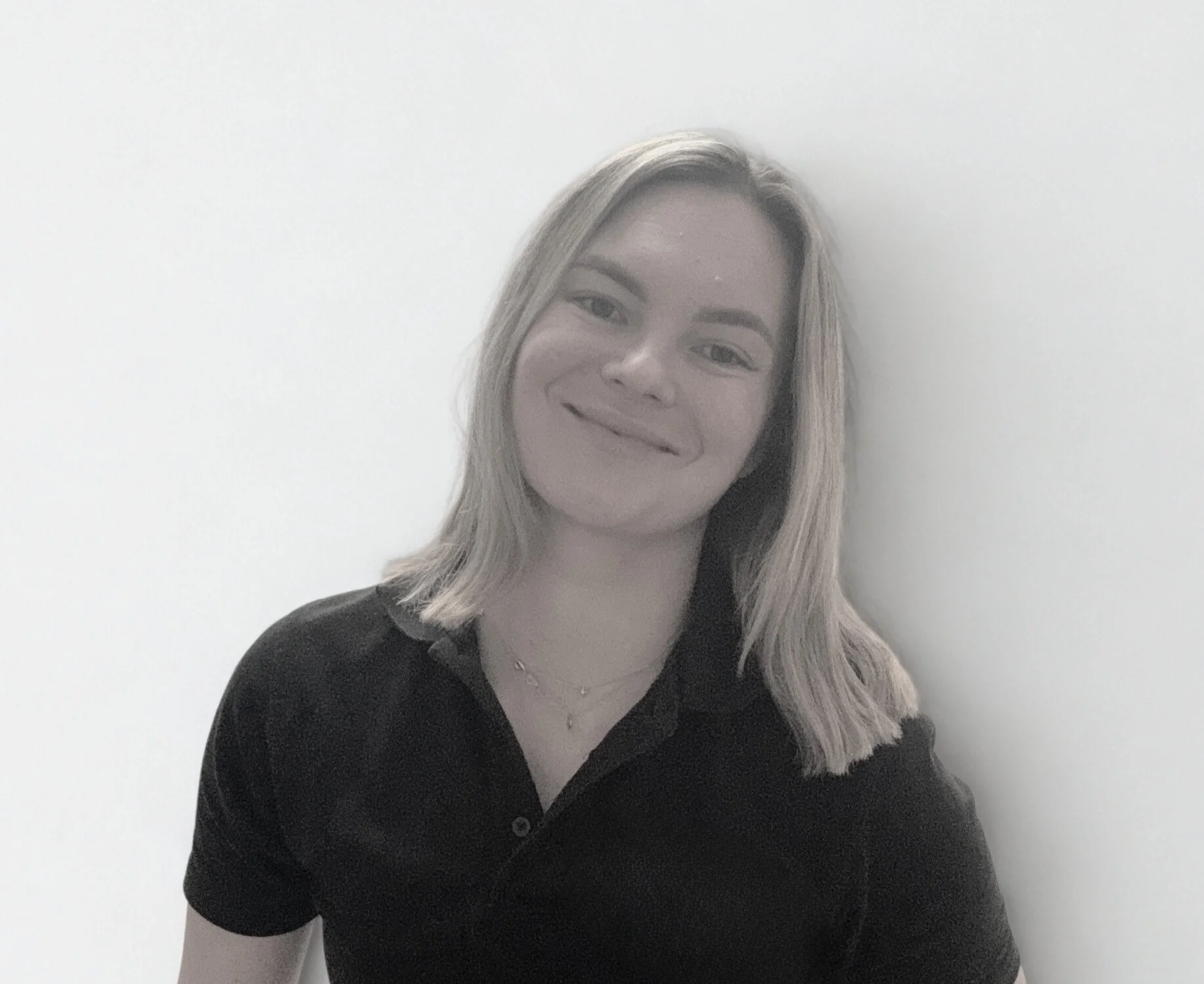Black and white photo of blonde physiotherapist wearing black polo smiling