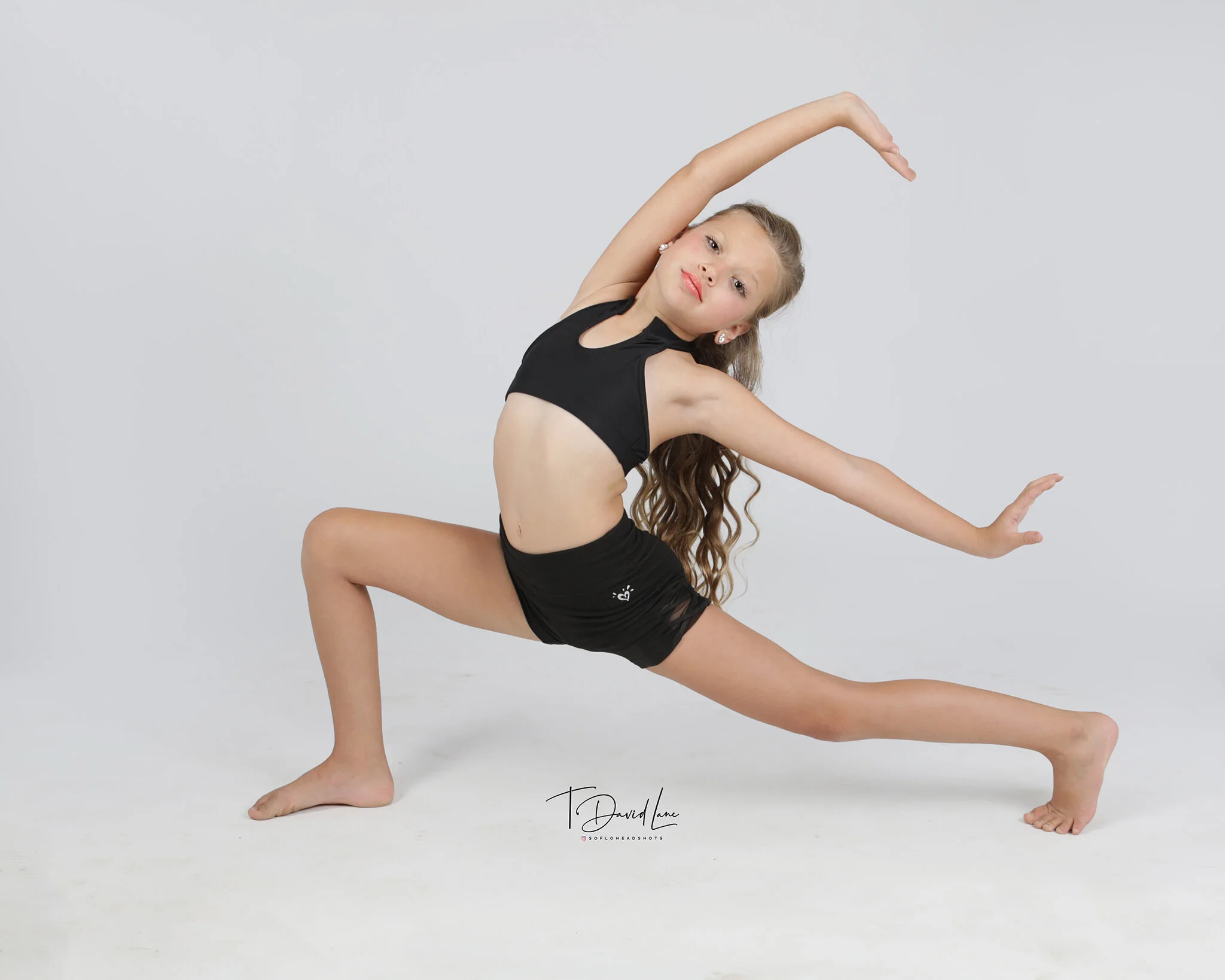Young female dancer performing an expressive contemporary dance pose against a light gray studio background.