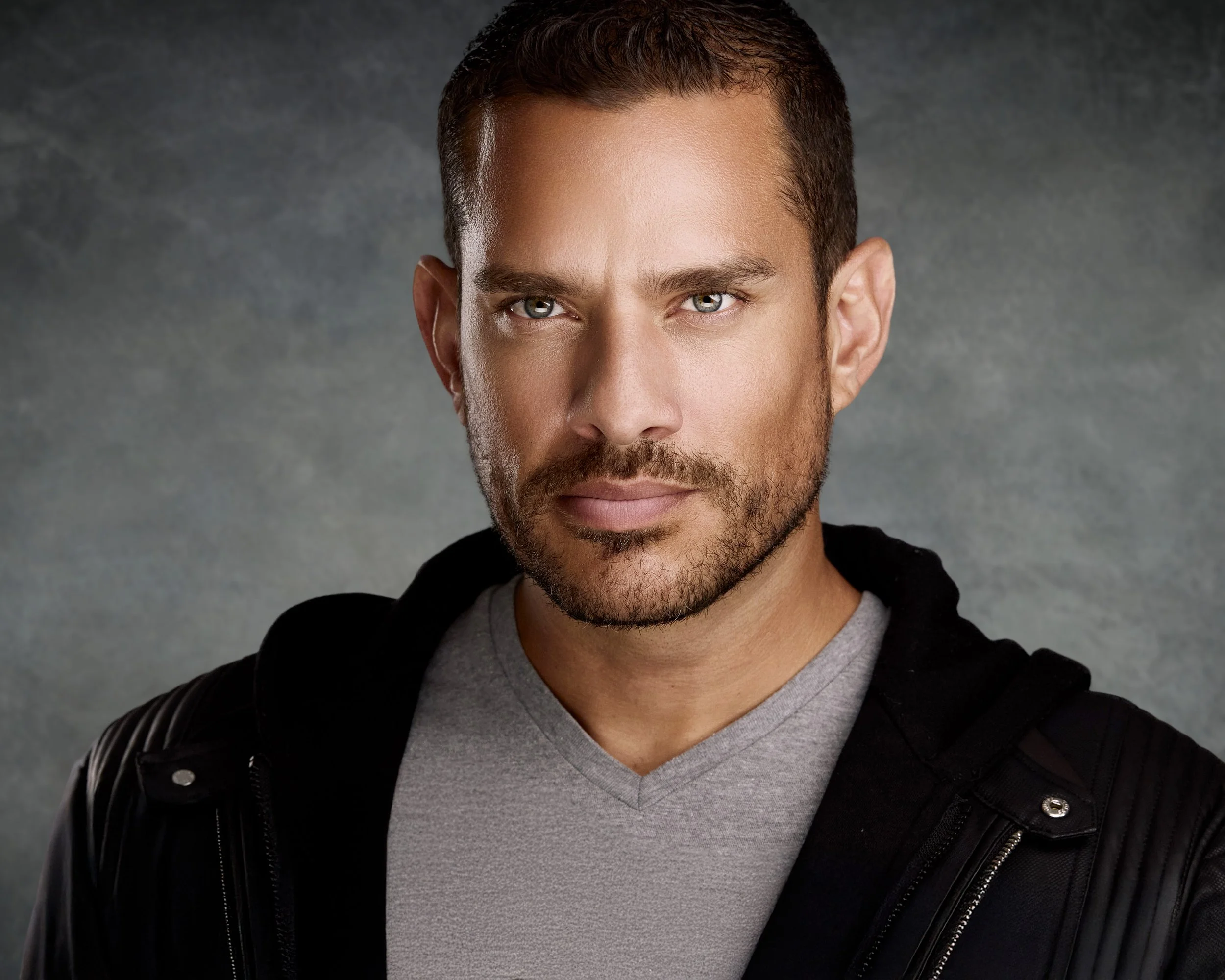 Professional male actor headshot in Miami featuring a confident expression, dramatic studio lighting, and a gray backdrop.