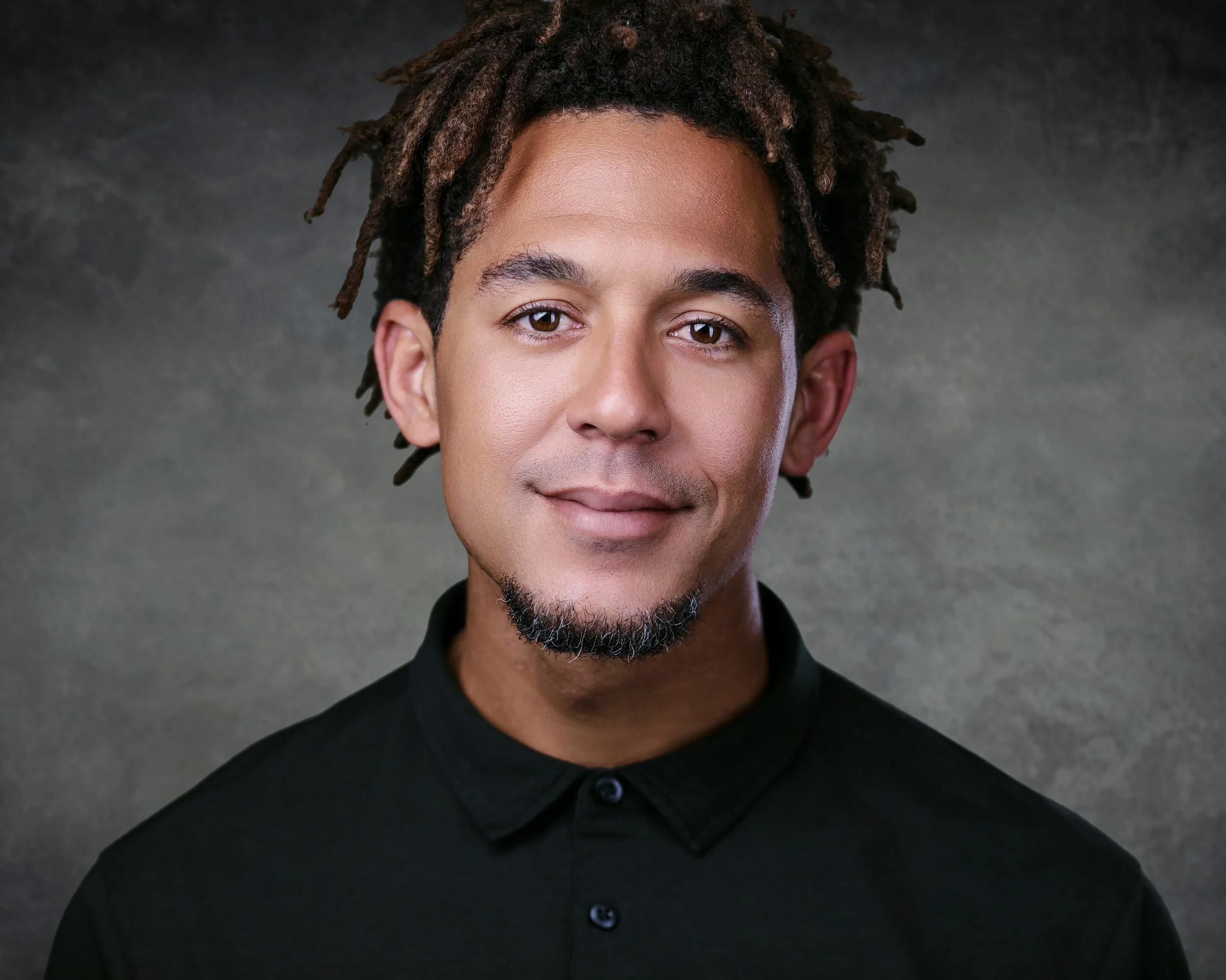 Professional male business headshot photographed in Miami, featuring a relaxed expression and studio lighting against a gray background.